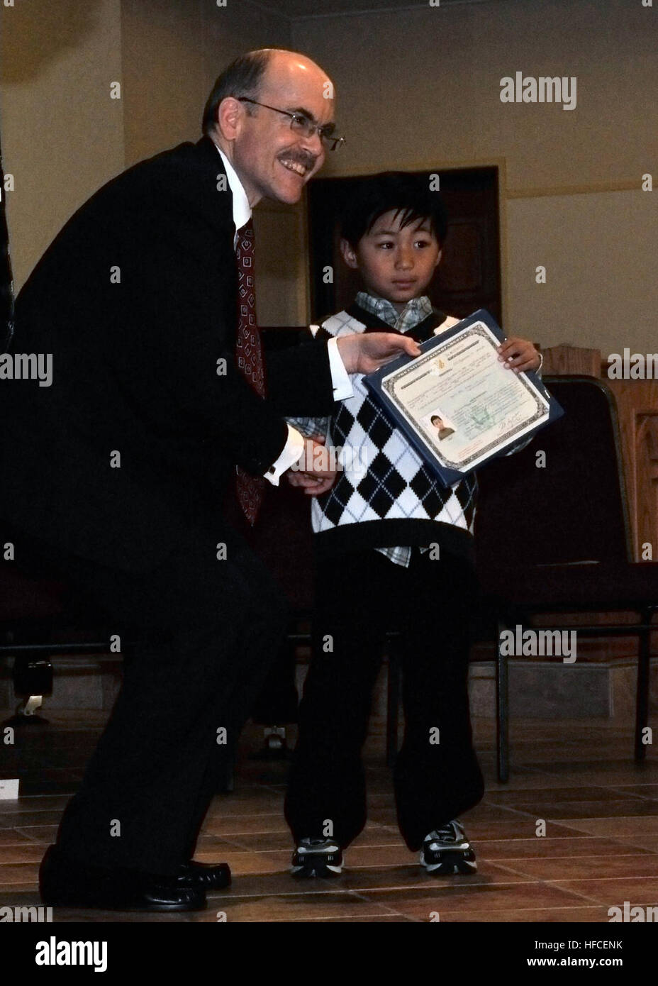 James P. Zumwalt, Charge d'Affaires ad interim of U.S. Embassy Tokyo, presents a certificate of citizenship to 7-year-old Martin Ulsano during a naturalization ceremony at Fleet Activities Yokosuka's Chapel of Hope. Ulsano is the first child to be naturalized overseas under the National Defense Authorization Act of 2008. The new citizens, more than 70 service members and family members come from diverse backgrounds, hailing from China, Columbia, Dominican Republic, Ecuador, El Salvador, England, France, Ghana, Guyana, Haiti, Jamaica, Japan, Kenya, Korea, Mexico, Morocco, Philippines, Romania,  Stock Photo