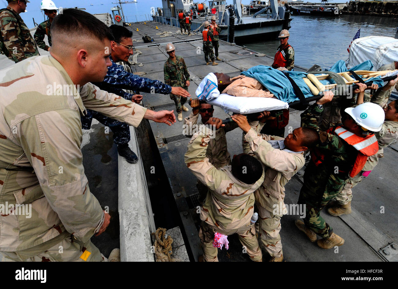 Sailors from Assault Craft Unit 2, Amphibious Construction Battalion 2, and USS Gunston Hall move a stretcher carrying a Haitian woman returning home after being medically treated on the Military Sealift Command hospital ship USNS Comfort at Killick Haitian Coast Guard Base. All three commands are taking part in Haitian relief efforts as part of Operation Unified Response. Naval commanders visit Haiti relief efforts 249289 Stock Photo