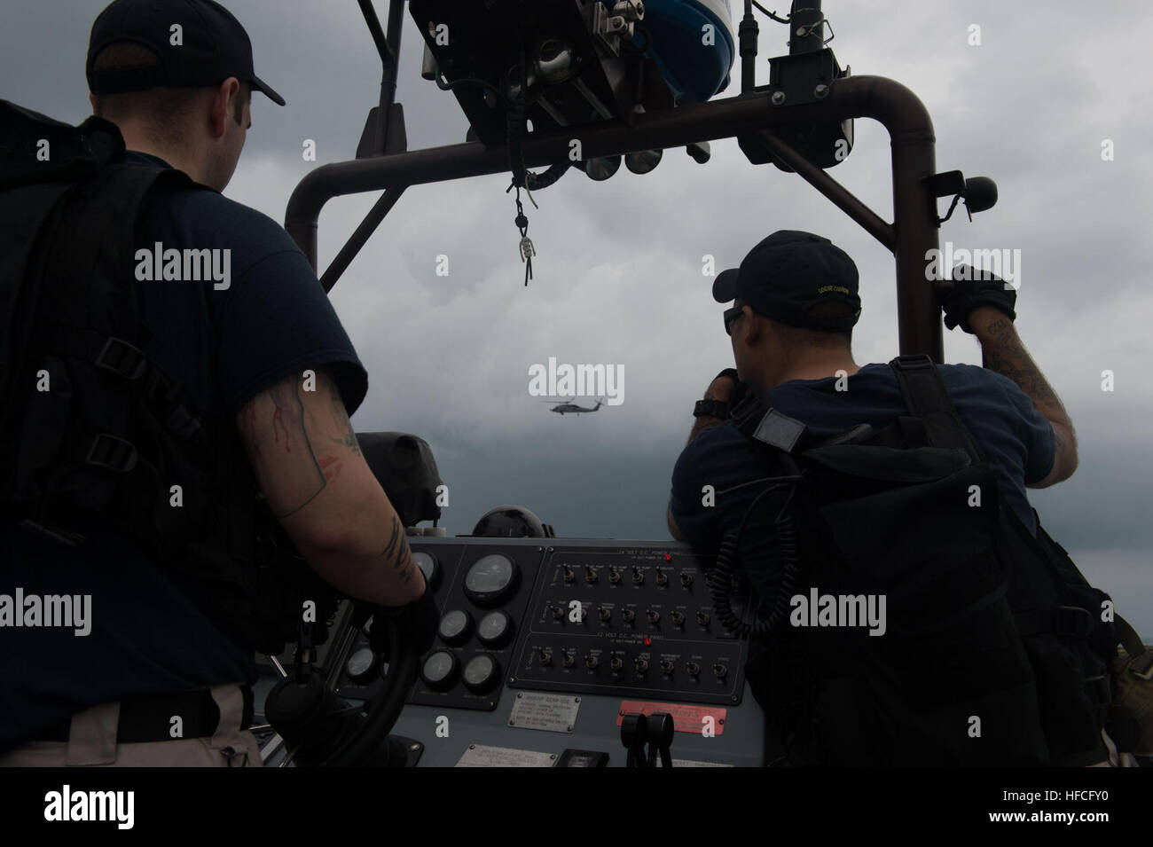 Sailors from littoral combat ship USS Fort Worth (LCS 3) conduct a surface search on a 11-m rigid hull inflatable boat while the ship’s MH-60R Seahawk flies overhead during air search operations. Fort Worth is currently on station in the Java Sea and supporting Indonesian-led efforts to locate missing AirAsia Flight QZ8501. (U.S. Navy photo by Mass Communication Specialist MC2 Antonio P. Turretto Ramos/Released) Navy divers support AirAsia Flight QZ8501 search efforts 150104-N-DC018-300 Stock Photo