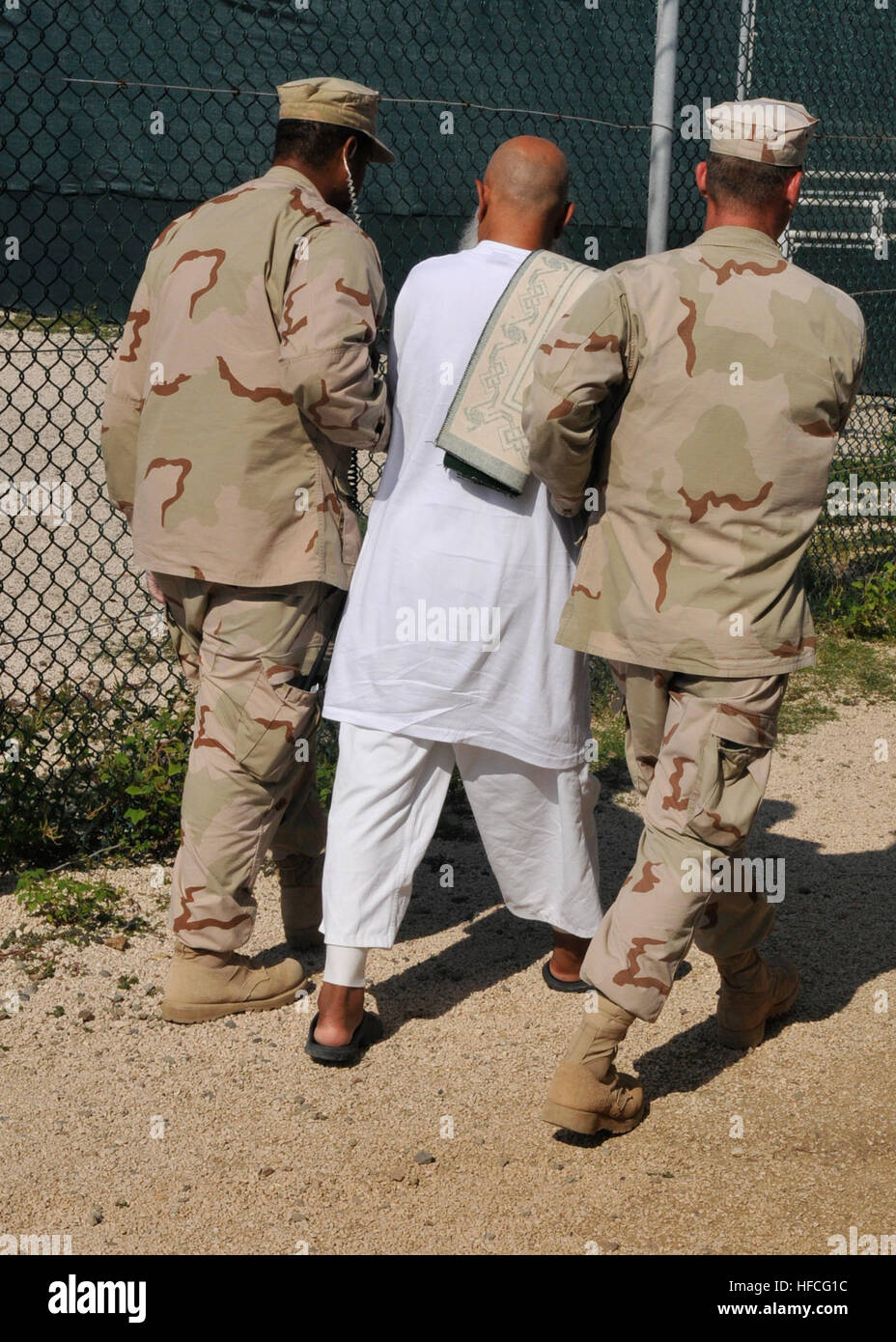 Sailors assigned to Navy Expeditionary Guard Battalion escort a detainee. Navy Expeditionary Guard Battalion provides 30 percent of the guard force inside the detention facilities at Joint Task Force Guantanamo. Navy Expeditionary Guard Battalion 341276 Stock Photo