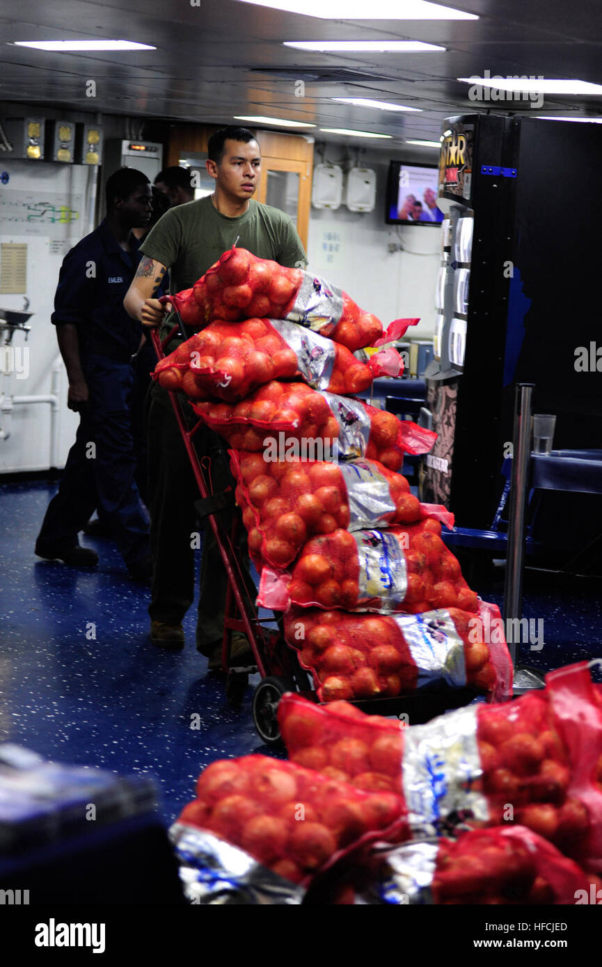 Cpl. Antonio Hernandez, assigned to the 13th Marine Expeditionary Unit (MEU), transports sacks of onions to the mess decks aboard the amphibious assault ship USS Boxer (LHD 4). Boxer is the flagship for the Boxer Amphibious Ready Group and, with the embarked 13th Marine Expeditionary Unit, is deployed in support of maritime security operations and theater security cooperation efforts in the U.S. 5th Fleet area of responsibility. (U.S. Navy photo by Mass Communication Specialist Seaman Veronica Mammina/Released) Onions, onions, onions! 131014-N-GM561-132 Stock Photo