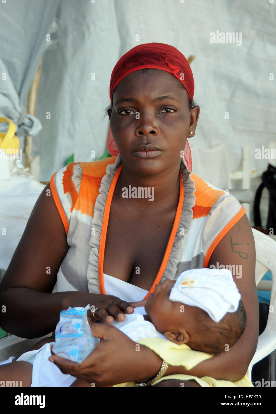 A Haitian mother braces her daughter against her chest as she waits for