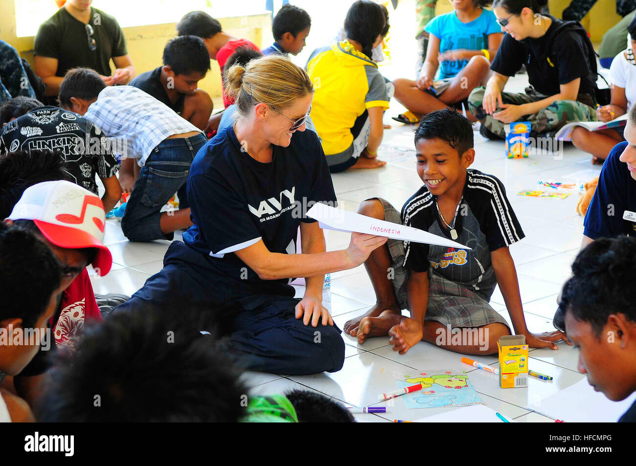New Zealand Defense Force Lt. Cmdr. Kerry Climo, embarked aboard the Military Sealift Command hospital ship USNS Mercy, gives a boy a paper airplane she made while spending time with children at the Rumah Sejahtera Bagi Anak Orphanage during a Pacific Partnership 2010 community service event. Pacific Partnership 2010 is the fifth in a series of annual U.S. Pacific Fleet humanitarian and civic assistance endeavors to strengthen regional partnerships. Pacific Partnership 2010 action 300850 Stock Photo