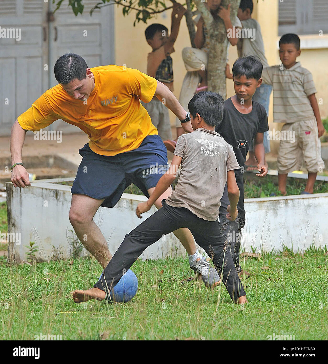 U.S. Navy Hospital Corpsman 3rd Class Alex Criollo plays soccer with Cambodian children during a Pacific Partnership 2012 community service event at Beung Pring Primary School, Aug. 7, 2012, in Sihanoukville, Cambodia Pacific Partnership is an annual deployment of forces designed to strengthen maritime and humanitarian partnerships during disaster relief operations, while providing humanitarian, medical, dental and engineering assistance to nations of the Pacific. (U.S. Navy photo by Mass Communication Specialist 2nd Class Roadell Hickman) Pacific Partnership 2012 120807-N-KW566-003 Stock Photo