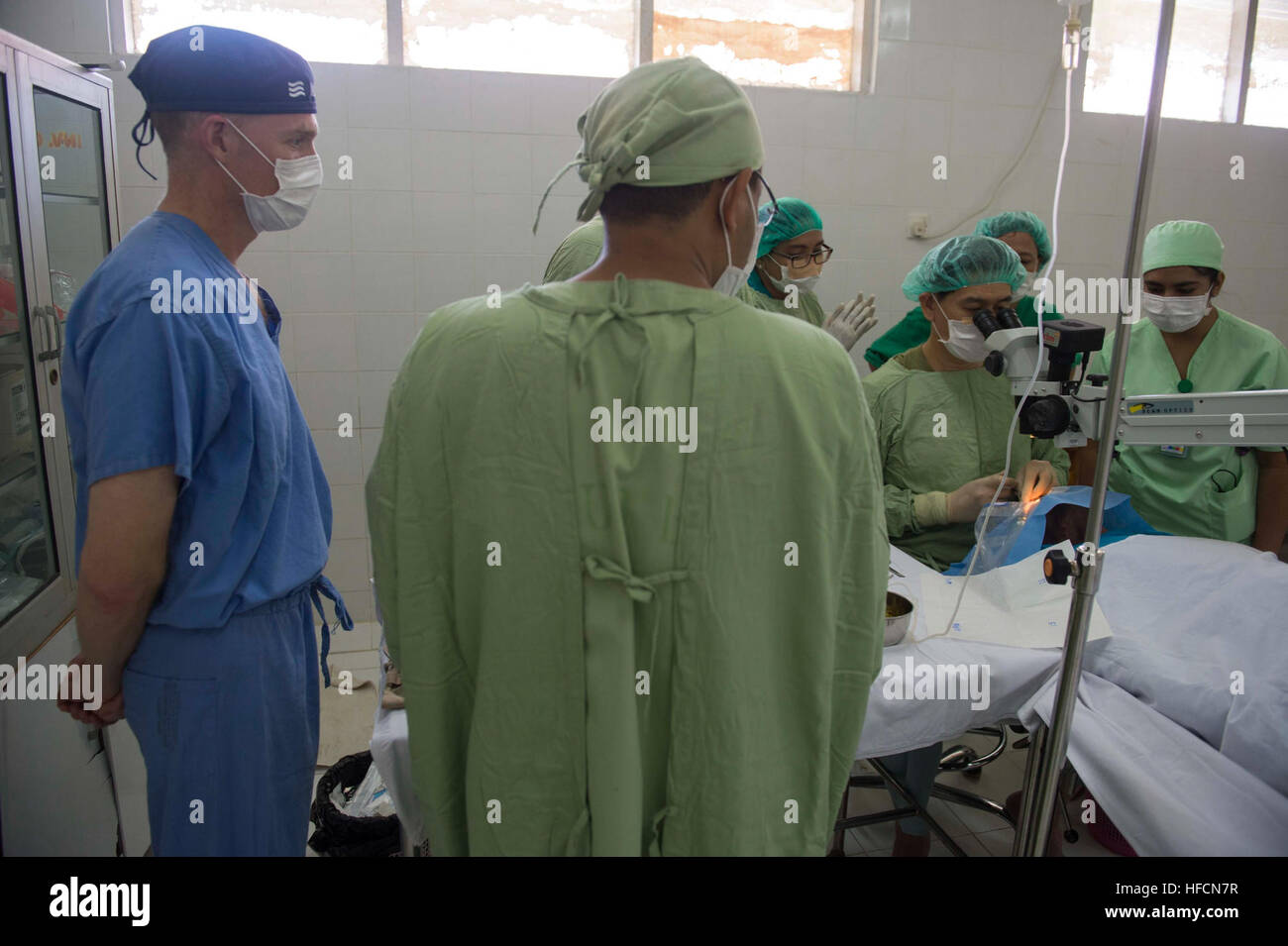 140528-N-IL267-083 BA'A, Indonesia (May 28, 2014) U.S. Navy Cmdr. Brice Nicholson, an ophthalmologist from Gig Harbor, Wash., assigned to Naval Hospital Bremerton, Hospital Corpsman 2nd Class Adam Docekal, from Centerville, Mich., and assigned to Naval Medical Center San Diego, and other volunteers listen and assist as ophthalmologist Miranda Johannes explains to ophthalmologist Republic of Singapore Air Force Senior Lt. Col. Gerard Nah how to perform a cataract surgery not typically used in Singapore or the United States during a subject matter expert exchange at Ba’a Subdistrict General Hosp Stock Photo