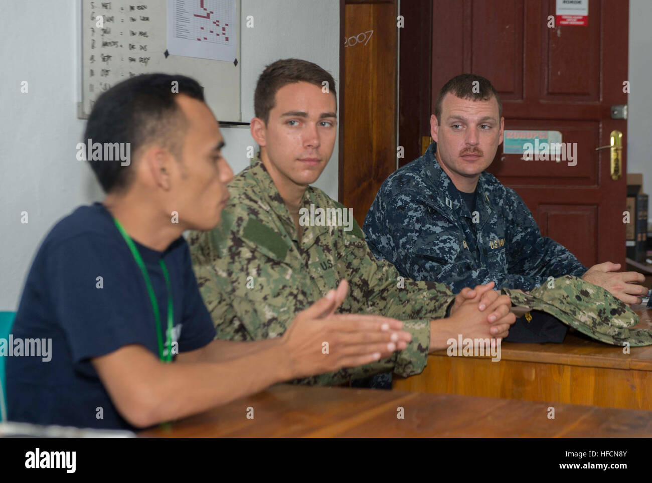From right, U.S. Navy Lt. Marcus McDonough, assigned to the Navy Entomology Center of Excellence, and Hospital Corpsman 2nd Class Dylan Rich, assigned to Navy Environmental and Preventive Medicine Unit 6, listen as Jimi Mane, a translator for Hope Worldwide, a nongovernmental organization, translates a question during an entomology subject matter expert exchange as part of Pacific Partnership 2014 in Ba'a, Indonesia, June 4, 2014. Pacific Partnership is an annual deployment of forces designed to strengthen maritime and humanitarian partnerships during disaster relief operations, while providin Stock Photo