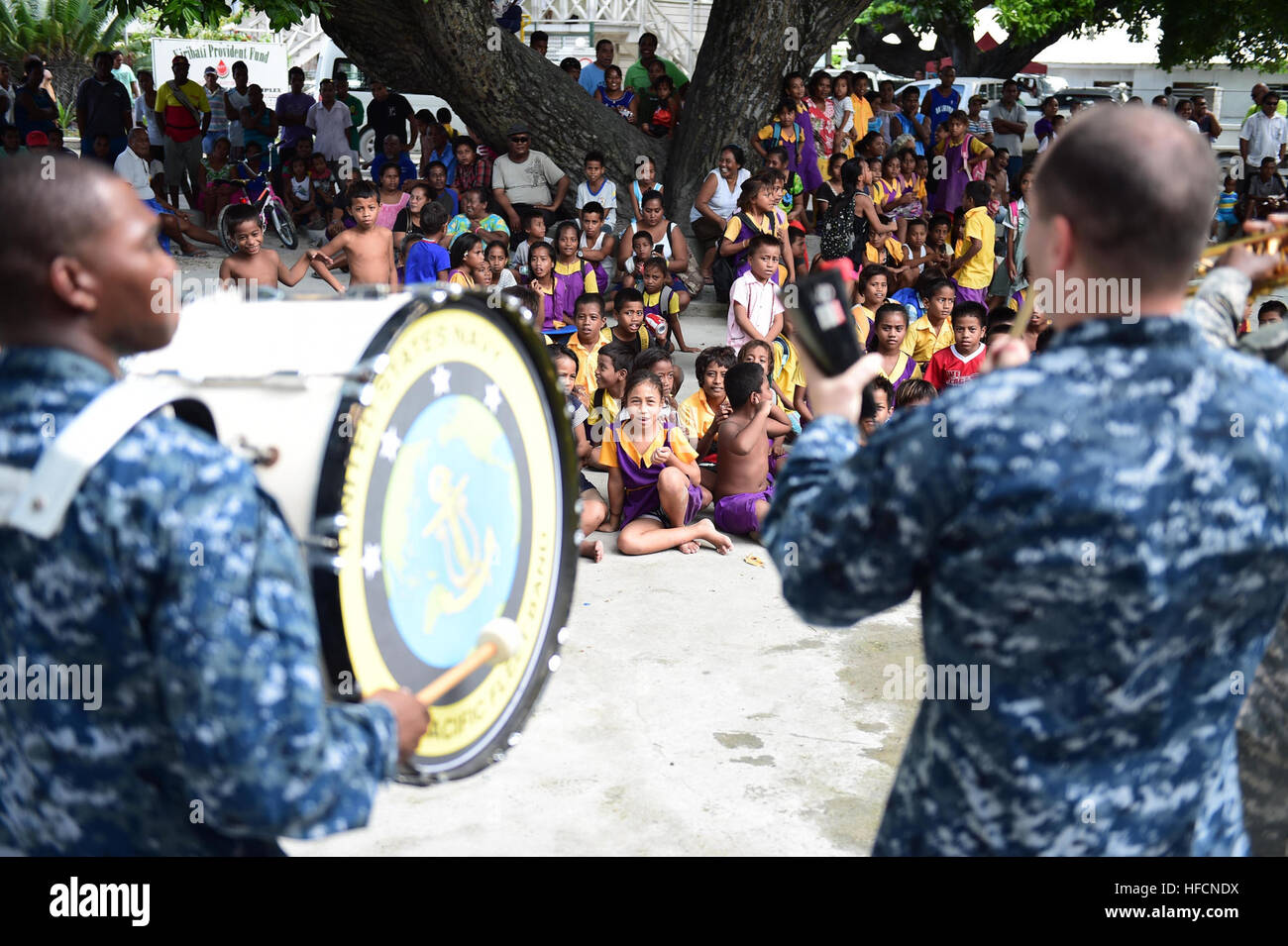 150604-N-HY254-181 TARAWA, Kiribati (June 4, 2015) Petty Officer 3rd Class Brian Mathis, left, and Petty Officer 1st Class David Baine, entertain a group of kids at a concert held in Bairiki Square during a Pacific Partnership visit to the Independent Republic of Kiribati. Both are members of the U.S. Pacific Fleet Band and are currently embarked with the Joint High Speed Vessel USNS Millinocket (JHSV 3). Millinocket is serving as the secondary platform for Pacific Partnership, led by an expeditionary command element from the Navy’s 30th Naval Construction Regiment (30 NCR) from Port Hueneme,  Stock Photo