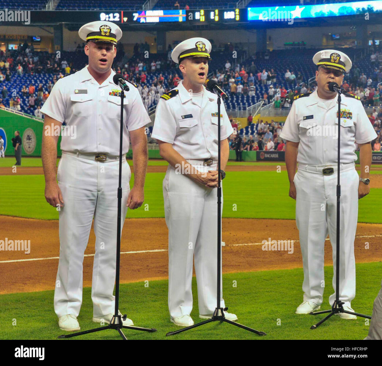 Ensign Christopher Boniwell, left, Lt. Justin Bernard, middle, and Lt. Joel Lopez, right, from the amphibious transport dock ship USS New York (LPD 21) sing 'God Bless America' during Military Appreciation Night at Marlins Park as part of Fleet Week Port Everglades. This is the 24th annual Fleet Week in Port Everglades, South Florida's annual celebration of the maritime services. (U.S. Navy photo by Mass Communication Specialist 2nd Class Cyrus Roson/Released) Port Everglades Fleet Week 2014 140430-N-YO707-509 Stock Photo