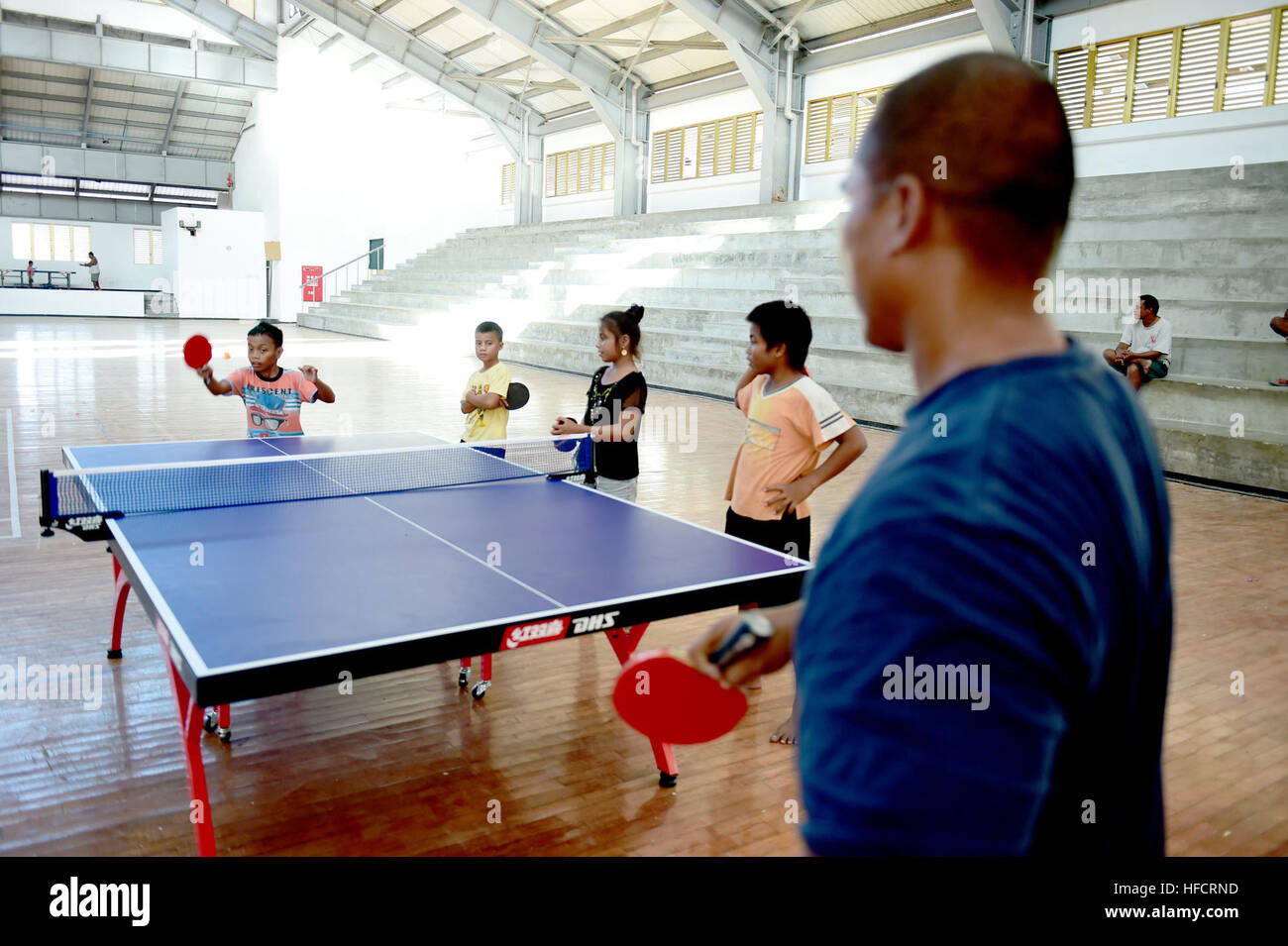 150603-N-HY254-111 TARAWA, Kiribati (June 3, 2015) Boatswain’s Mate 1st Class Kensley Raigeluw, from Honolulu Hawaii and currently assigned to Coast Guard District 14, plays a game of table tennis with I-Kiribati boy at the Betio Sports Complex during Pacific Partnership 2015.  Now in its tenth iteration, Pacific Partnership is the largest annual multilateral humanitarian assistance and disaster relief preparedness mission conducted in the Indio-Asia-Pacific region. While training for crisis conditions, Pacific Partnership missions have provided medical care to approximately 270,000 patients a Stock Photo