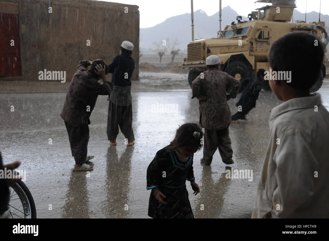 Farahi children run out to play in the rain and hail during an afternoon thunderstorm outside the site of a key leader engagement attended by members of Provincial Reconstruction Team (PRT) Farah in Farah City, Feb. 25.  Civilian and military representatives from the PRT visited a newly constructed Family Guidance Center operated by the Afghan-operated NGO Voice of Women in Farah City to discuss gender issues, conduct a site survey and monitor programming.  PRT Farah's mission is to train, advise, and assist Afghan government leaders at the municipal, district, and provincial levels in Farah p Stock Photo