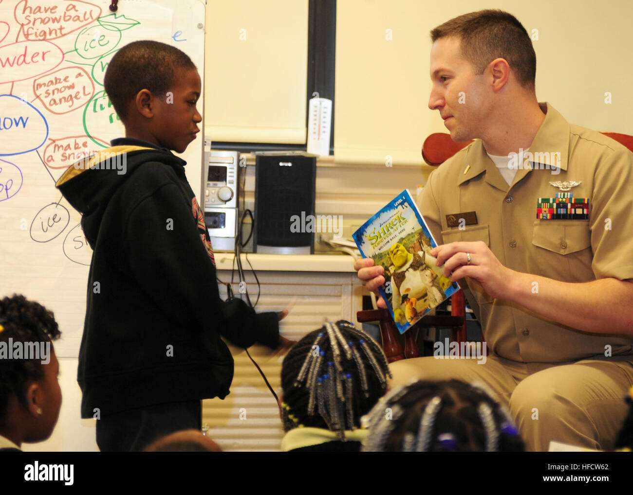 Ensign Mike Larson, media division officer aboard the aircraft carrier USS  Theodore Roosevelt, reads to students at Lindenwood Elementary School.  Sailors aboard Theodore Roosevelt raised $2,800 and donated more than 375  gifts,