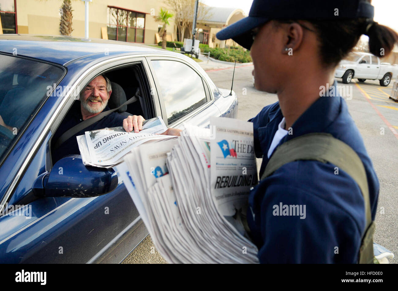 Seaman Laketta Thomas, a hospital corpsman assigned to the amphibious assault ship USS Nassau, passes out copies of the local newspaper at a distribution point where people affected by Hurricane Ike can receive food and water. Nassau is anchored off the coast of Galveston to support civil authorities in disaster recovery as directed in the wake of Hurricane Ike. Sailors distribute basic needs during food convoy in Galveston 117370 Stock Photo