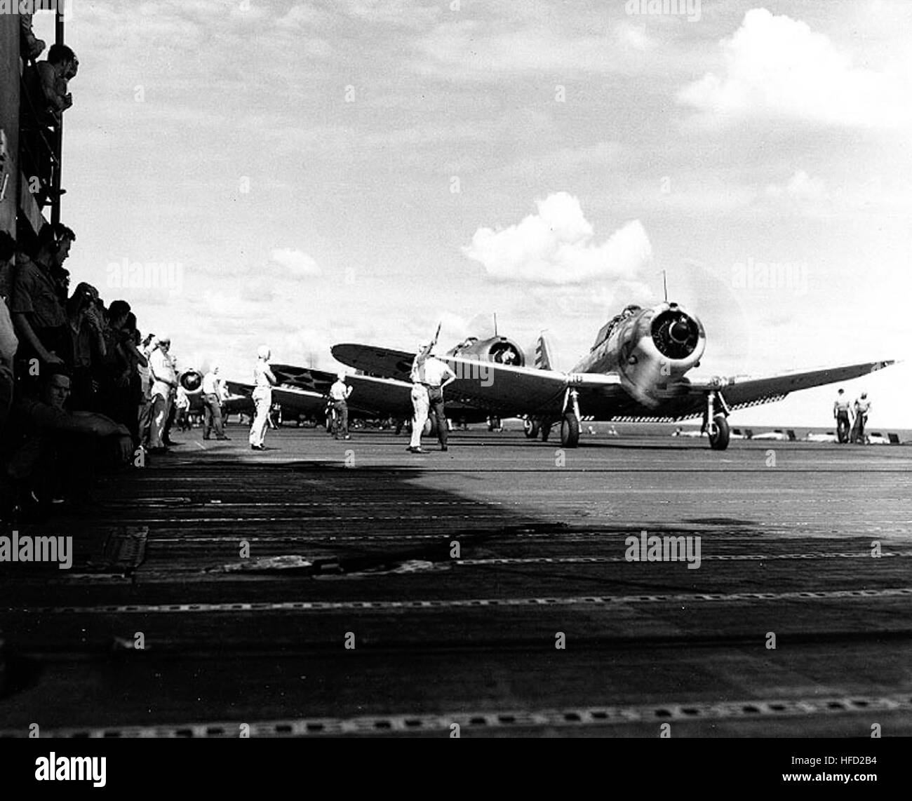 Douglas SBD-3 Dauntless scout bombers preparing to take off, during operations in the Coral Sea, 18 April 1942. The first plane is from Scouting Squadron Five (VS-5). Note that it has no insignia painted under its starboard wing, and that the insignia below its port wing is much smaller than that on the next SBD. Man standing at left, just beyond the first plane's wingtip, is Boatswain Chester E. Briggs, Jr.  Official U.S. Navy Photograph, now in the collections of the U.S. National Archives. SBDs take off from USS Yorktown (CV-5) in April 1942 Stock Photo