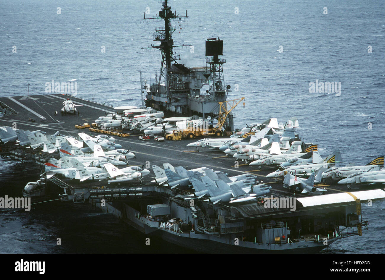 An elevated view of the flight deck of the aircraft carrier USS MIDWAY (CV 41).  Aircraft on the deck include, from front to back, (right side): F-4 Phantom II aircraft, EA-6B Prowler aircraft, A-6 Intruder and E-2 Hawkeye aircraft.  Planes on the left side include A-7 Corsair II aircraft and A-6 Intruder aircraft.  An SH-3 Sea King helicopter is visible in the background. Aerial view (aft) of USS Midway (CV-41) on 17 May 1984 Stock Photo