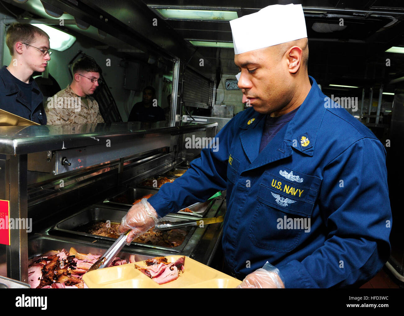 Chief Information Systems Technician Cesar Nunez serves Christmas dinner aboard the amphibious assault ship USS Boxer (LHD 4). Boxer is the flagship for the Boxer Amphibious Ready Group and, with the embarked 13th Marine Expeditionary Unit, is deployed in support of maritime security operations and theater security cooperation efforts in the U.S. 5th Fleet area of responsibility. (U.S. Navy Photo by Mass Communication Specialist 3rd Class Mayra A. Knight/Released) Serving Christmas dinner 131225-N-PZ713-023 Stock Photo