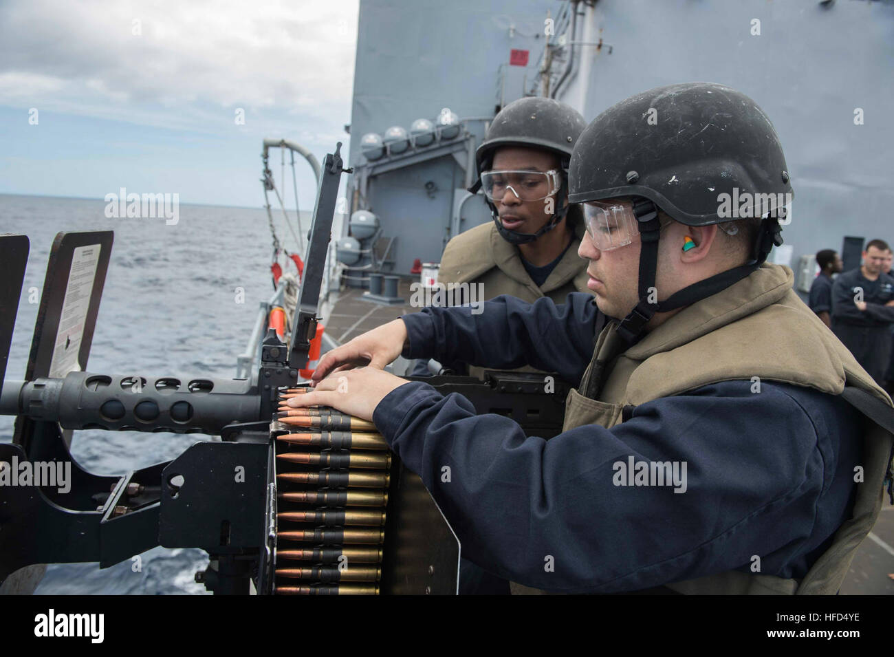 160225-N-RM689-254  SOUTH CHINA SEA (Feb. 25, 2016)- Culinary Specialist 2nd Class Edward Orsak, assigned to amphibious dock landing ship USS Ashland (LSD 48), loads the .50-caliber machine gun while Gunner’s Mate Seaman Robert White, one of Ashland’s firearms instructors, performs safety officer duties during a small craft attack team (SCAT) live fire drill. Ashland is assigned to the Bonhomme Richard Amphibious Ready Group (BHRARG) and is conducting a routine patrol in the 7th Fleet area of responsibility. (U.S. Navy photo by Mass Communication Specialist Seaman Kelsey L. Adams/Released) Sma Stock Photo