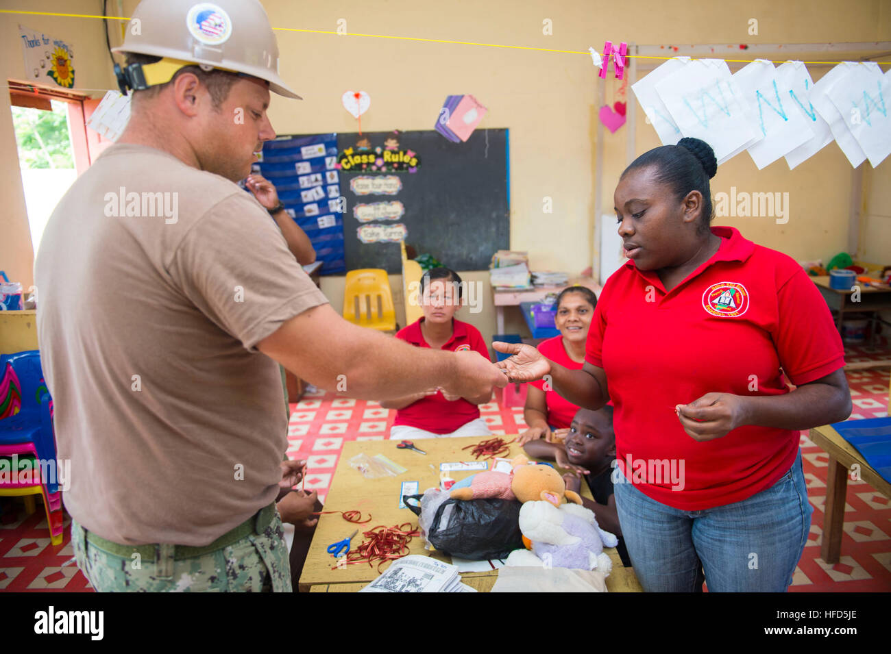 U.S. Navy Builder 2nd Class Adam Jones gives school teacher Alida Kimberly Warrior a challenge coin at Bethel SDA School during Southern Partnership Station 2014 (SPS-JHSV 14). Southern Partnership Station 2014 is a U.S. Navy deployment focused on subject matter expert exchanges with partner nation militaries and security forces. U.S. Naval Forces Southern Command and U.S. 4th Fleet employ maritime forces in cooperative maritime security operations in order to maintain access, enhance interoperability, and build enduring partnerships that foster regional security in the U.S. Southern Command a Stock Photo