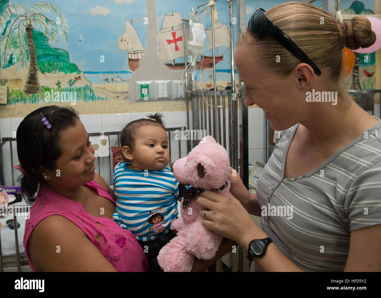 U.S. Navy Lt. Kimberly Herm, gives a teddy bear to an Honduran child at the Hospital Dr. Salvador Paredes pediatric ward during Southern Partnership Station 2014 (SPS-JHSV 14). Southern Partnership Station 2014 is a U.S. Navy deployment focused on subject matter expert exchanges with partner nation militaries and security forces. U.S. Naval Forces Southern Command and U.S. 4th Fleet employ maritime forces in cooperative maritime security operations in order to maintain access, enhance interoperability, and build enduring partnerships that foster regional security in the U.S. Southern Command a Stock Photo