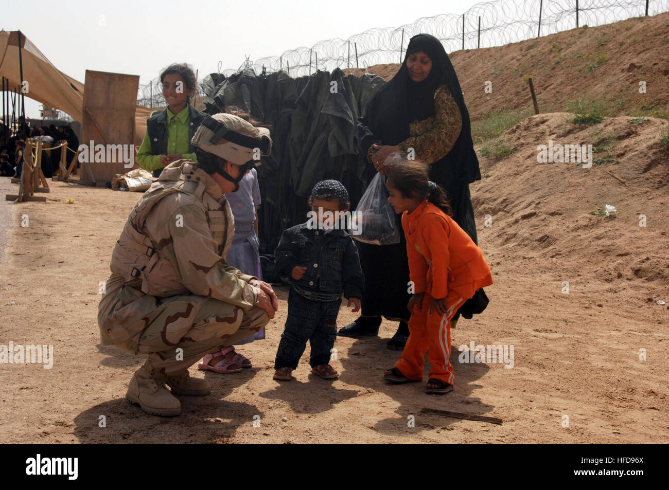 The Navy Provisional Detainee Battalion Chaplain, Cmdr. Anne Krekelberg plays with an Iraqi child as he waits at the Camp Bucca Visitors Center to see a relative who is being detained at the Theater Internment Facility. In addition to guaranteed due process reviews, access to 24-hour medical care and culturally appropriate meals, detainees are authorized to receive family visits. Krekelberg is a Navy individual augmentee from the 22nd Naval Construction Regiment based in Gulfport, Miss. More than 400 Sailors from 254 commands worldwide make up the Navy Provisional Detainee Battalion. (U.S. Nav Stock Photo
