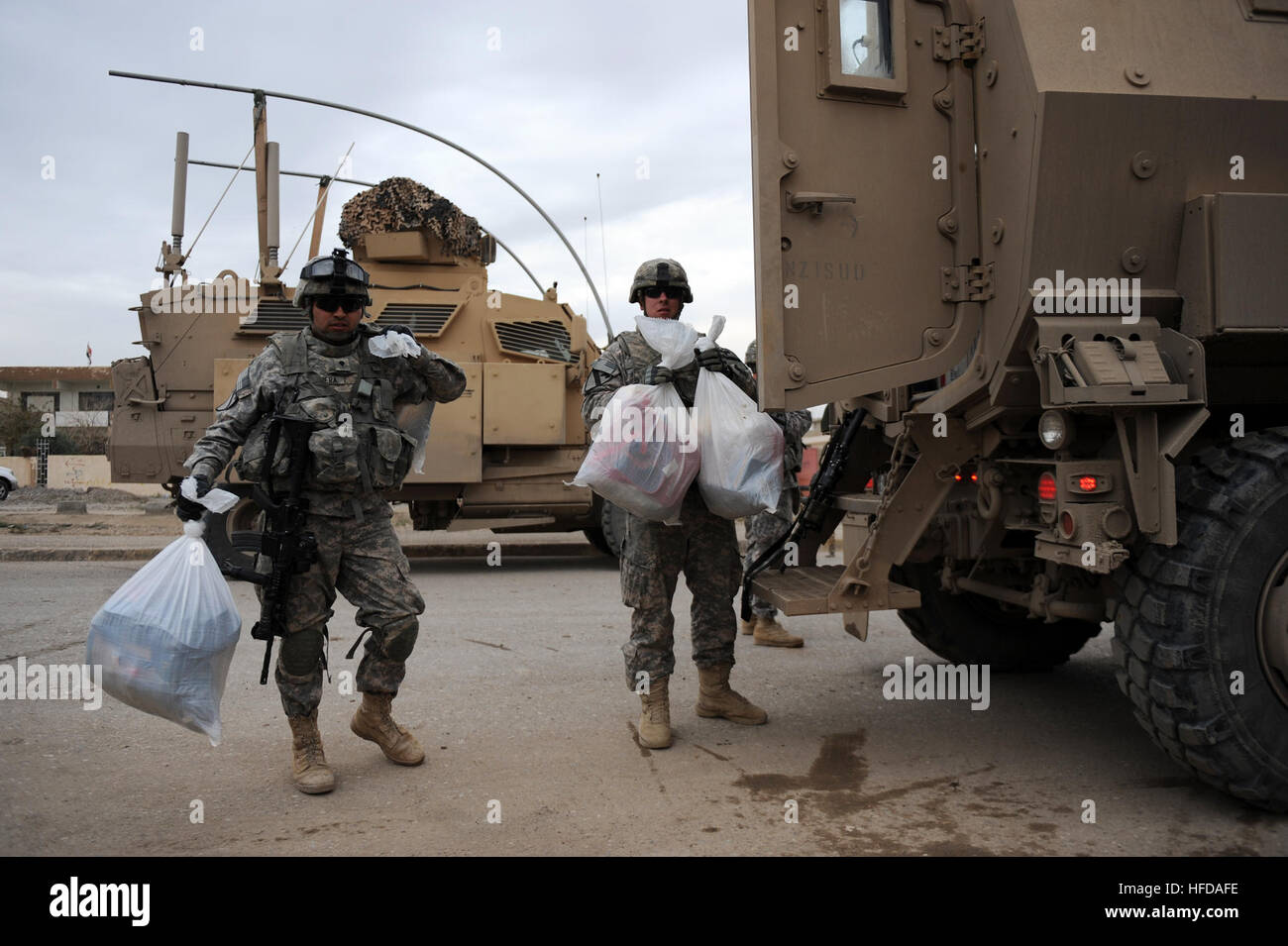 Spc. Emmanuel Madera and Spc. Jerrad Spruell, from the 1st Cavalry Division, 2nd Brigade Combat Team, 9th Cavalry, 4th Squadron, 3rd Platoon (4-9 Cav), carry toys into the Youth Center in Darquq, Iraq, Nov. 25, 2009. The 4-9 Cav and the Daquq police department delived toys and supplies to more than 150 children gathered at the Youth Center in honor of the Iraqi Junior Heroes Program, which is designed to help children become more comfortable with Iraqi security forces, and teach children what they can do to strengthen their community.  (U.S. Navy photo by Mass Communication Specialist 2nd Clas Stock Photo
