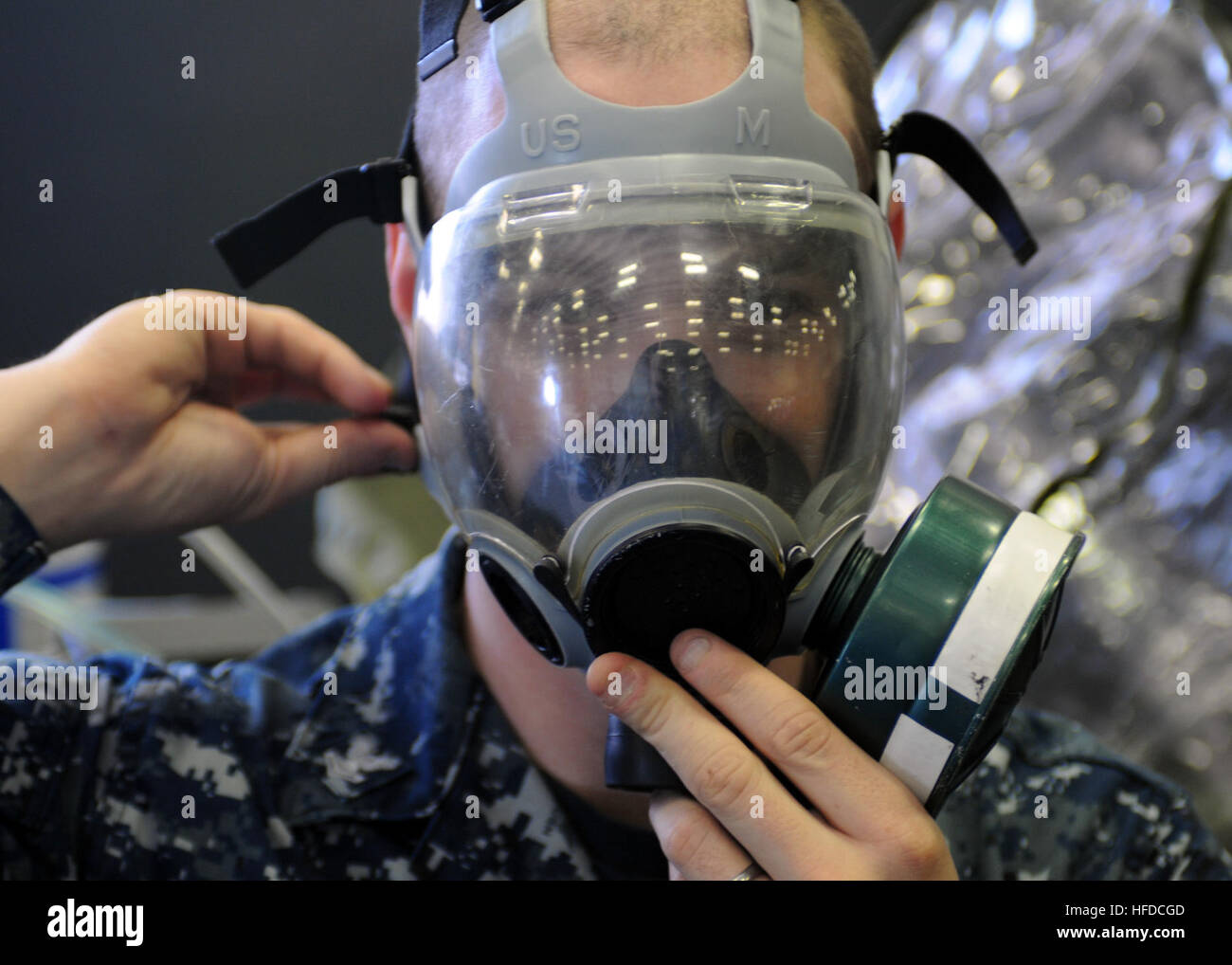 U.S. Navy Aviation Structural Mechanic 2nd Class Thomas Jenkins, assigned to amphibious assault ship USS Makin Island (LHD 8), checks the air seal on his respirator mask during chemical, biological and radiological equipment testing in the ship's hangar bay Jan. 13, 2011, in San Diego, Calif. Makin Island was completing a maintenance availability period in preparation for predeployment operations. (U.S. Navy photo by Mass Communication Specialist 2nd Class Kellie Abedzadeh/Released) U.S. Navy Aviation Structural Mechanic 2nd Class Thomas Jenkins, assigned to amphibious assault ship USS Makin I Stock Photo