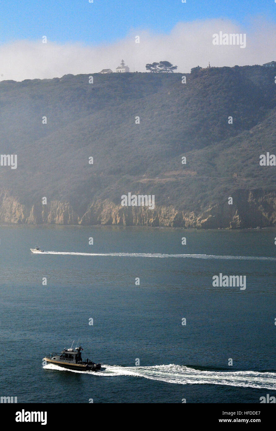 A U.S. Navy security craft passes past the historic Point Loma Lighthouse while escorting the amphibious assault ship USS Boxer out to sea. Boxer is supporting the 13th Marine Expeditionary Unit Certification Exercise to prepare for an upcoming deployment. U.S. Navy security craft 134664 Stock Photo