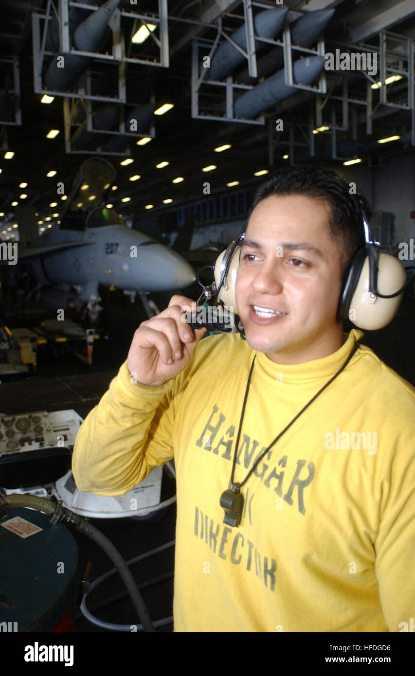 020324-N-0283O-002 At sea aboard USS Kitty Hawk (CV 63) Mar. 24, 2002 -- Aviation Boatswain's Mate 3rd Class Enrique Manriquez from La Puente, CA, communicates with personnel on the flight deck via his headset radio, while coordinating aircraft movements to and from the ship's flight deck and hangar bay.  Kitty Hawk is conducting work-ups in preparation for an upcoming extended underway period and is the Navy's only permanently forward-deployed aircraft carrier, operating out of Yokosuka, Japan.  U.S. Navy photo by Photographer's Mate Airman Sean M. O'Leary.  (RELEASED) US Navy 020324-N-0283O- Stock Photo