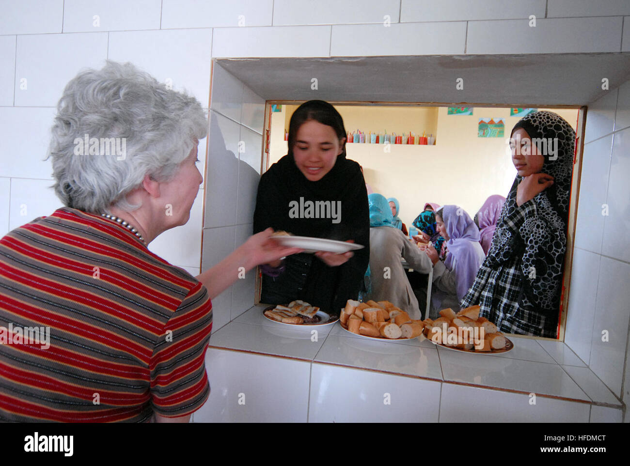 100411-N-9594C-072 KABUL, Afghanistan (April 11, 2010) –Le Pelican School director, Ariane Hiriart, left, passes a student’s plate of food to Fawzia, school supervisor, during lunch. The school currently has 204 students, ranging in age from eight to thirty-three, who are taught hygiene, math, Dari, Pashto, English, science, geography and other subjects. The school also teaches valuable life skills in a fully functioning bakery that sells baguettes, croissants and other French-style breads in the near-by area. A team from the Volunteer Community Relations program at Camp Eggers visited the sch Stock Photo
