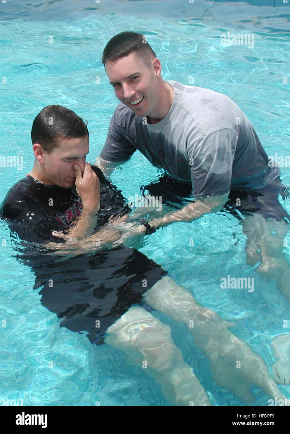 030503-N-6197C-002 Aboard USS Boxer (LHD 4) in port Jebel Ali (May 3, 2003) -- Chaplain Bellar, ShipÕs Chaplain, performs a Christian baptism on Storekeeper Ryan P. Schoch in a pool.  The Boxer is in port Jebel Ali, a city in Dubai, UAE.  Boxer is deployed to the Arabian Gulf in support of Operation Iraqi Freedom the multi-national coalition effort to liberate the Iraq's weapons of mass destruction, and end the regime of Saddam Hussein.  U.S. Navy photo by LithographerÕs Mate 3rd Class Sadie Conklin.  (RELEASED) Baptism in a pool Stock Photo