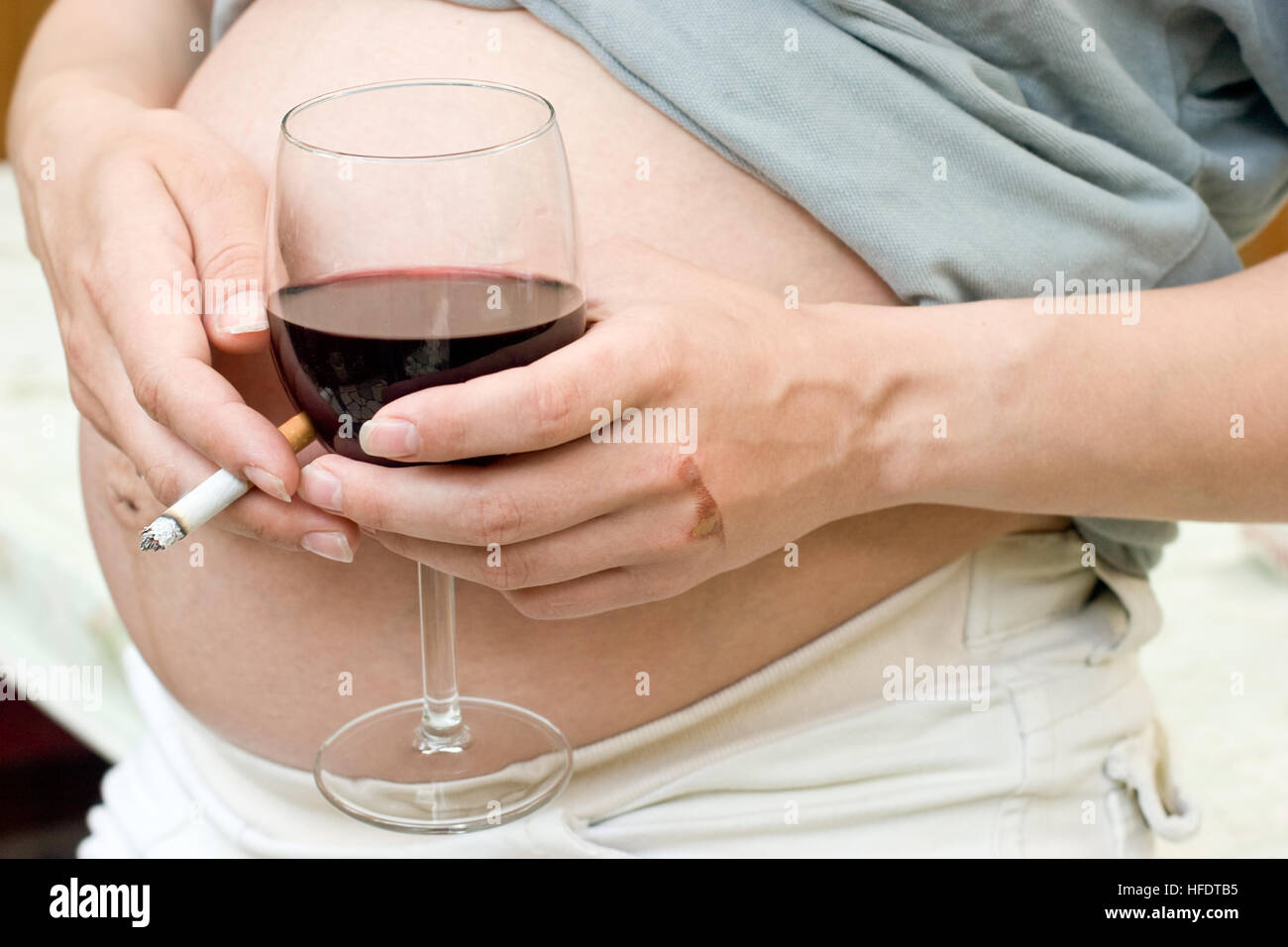 Young pregnant woman holding wine and cigarette Stock Photo