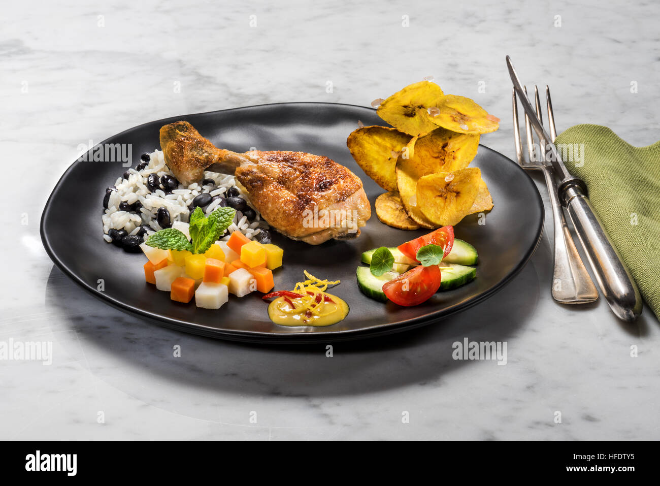 Typical Cuban food, chicken, rice with black beans, fried banana chips, salad and vegetables. CUBA. kuba FOOD Style styling food Stock Photo