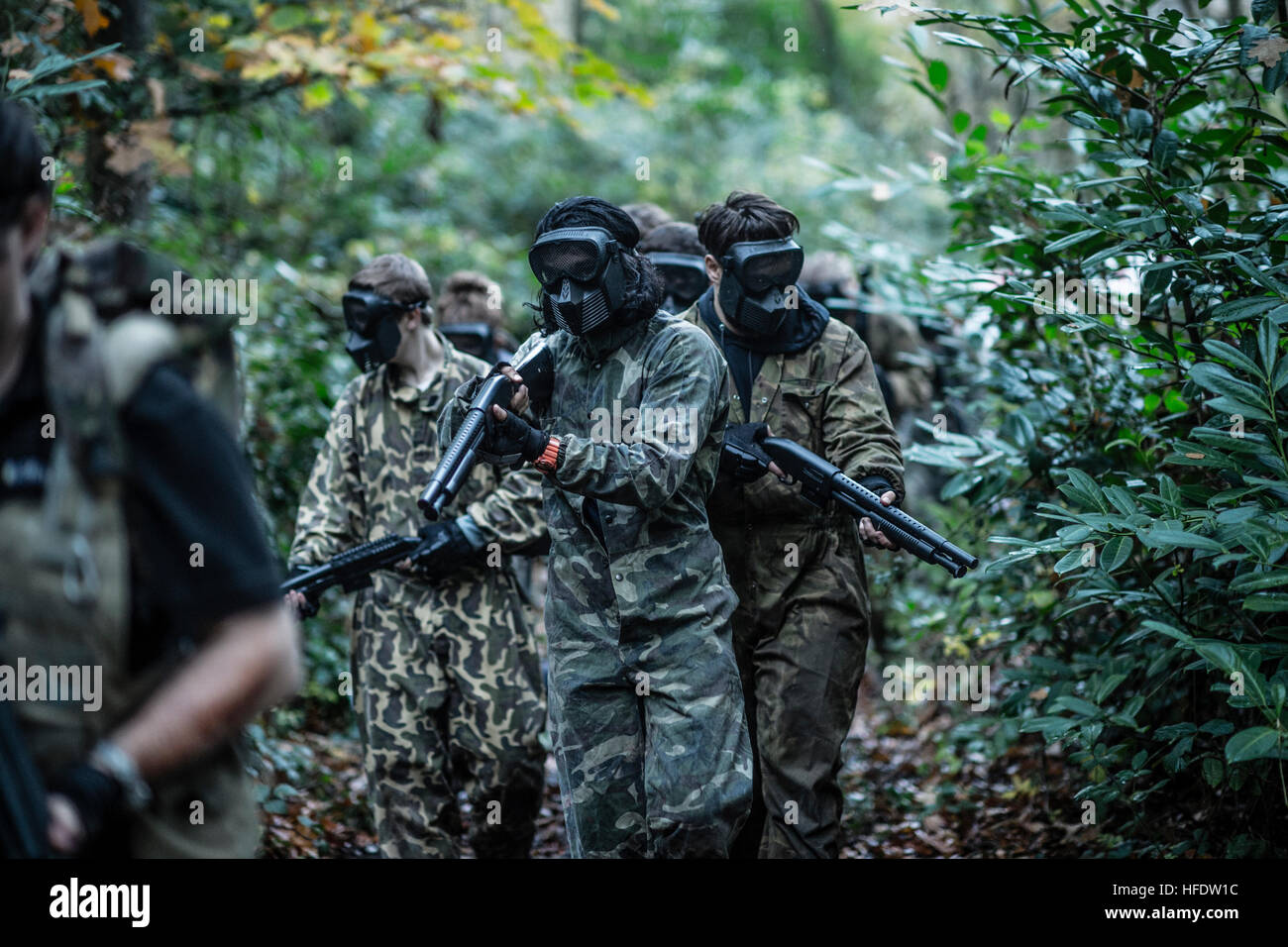 Groups of people dressed up in combat camouflage  uniforms and carrying paint-ball guns hunting zombies in the woods in a 'The Walking Dead Experience' Live Action Role Play  (LARP) activity event on a November afternoon in woodlands near Aberystwyth Wales UK Stock Photo