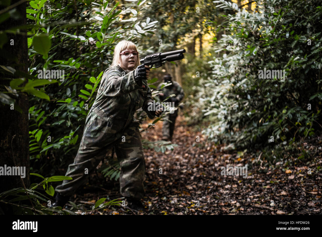 Groups of people dressed up in combat camouflage uniforms and carrying paintball guns hunting