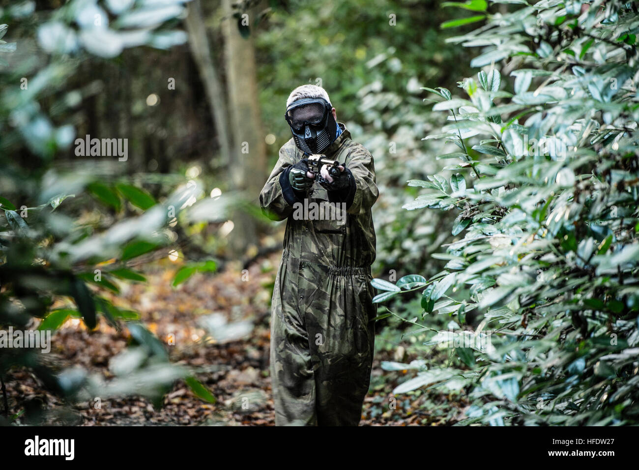 Groups of people dressed up in combat camouflage uniforms and carrying paintball guns hunting