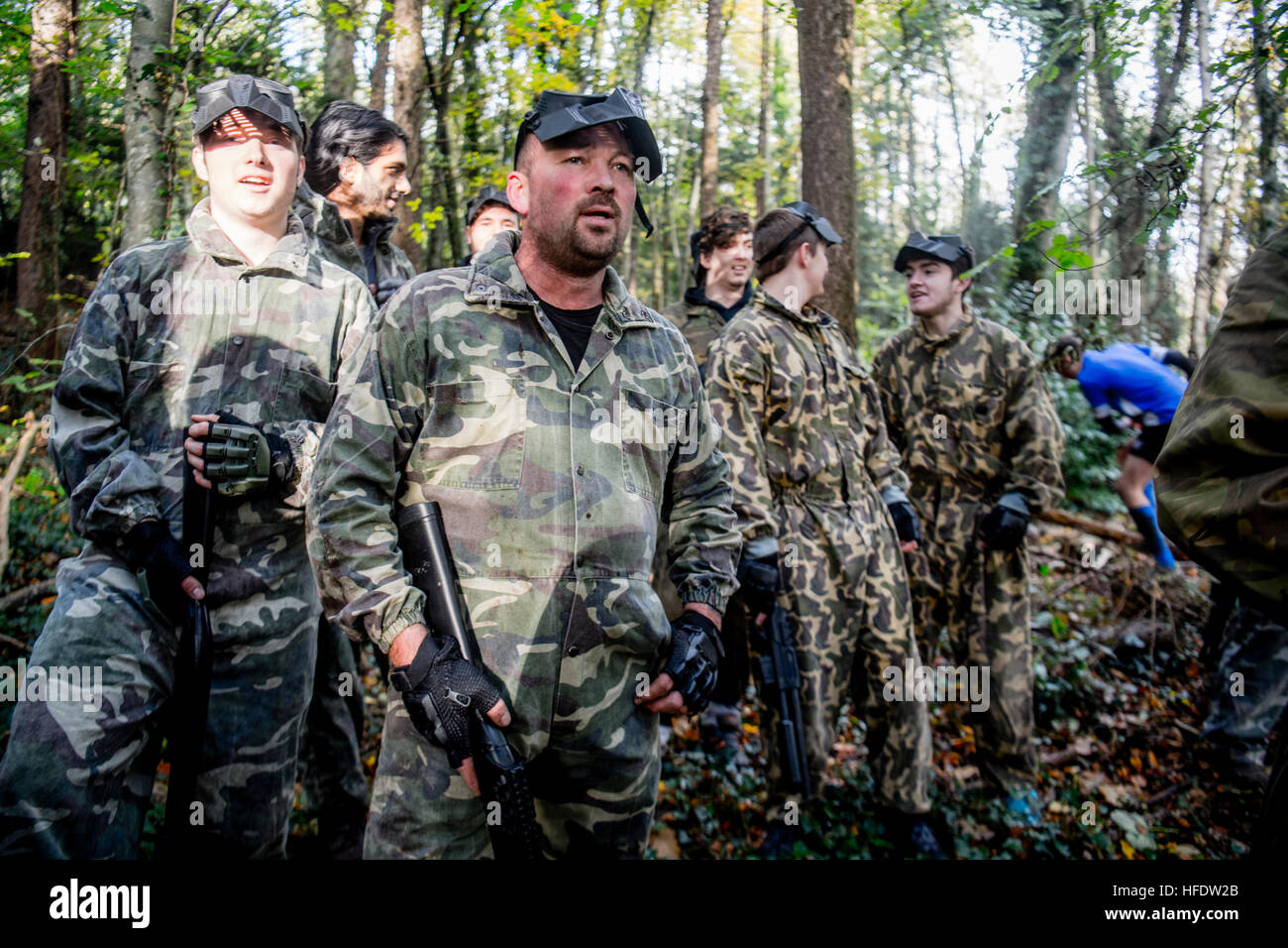 Groups of people dressed up in combat camouflage uniforms and carrying paintball guns hunting