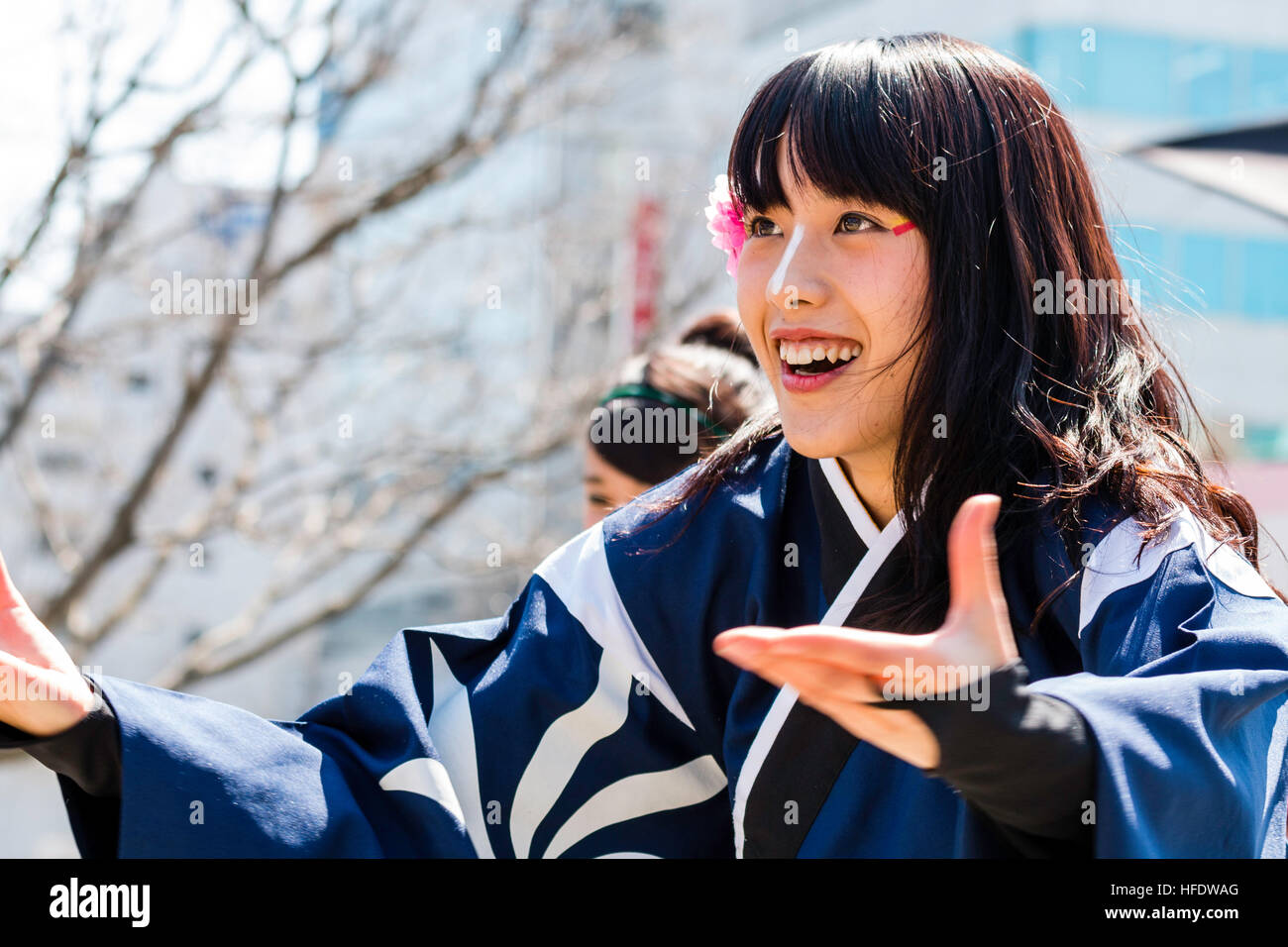 Japan, Kumamoto. Hinokuni Yosakoi Festival. Woman dancer with flower in hair. Face, smiling with mouth open, happy. hands and arms outstretched. Stock Photo