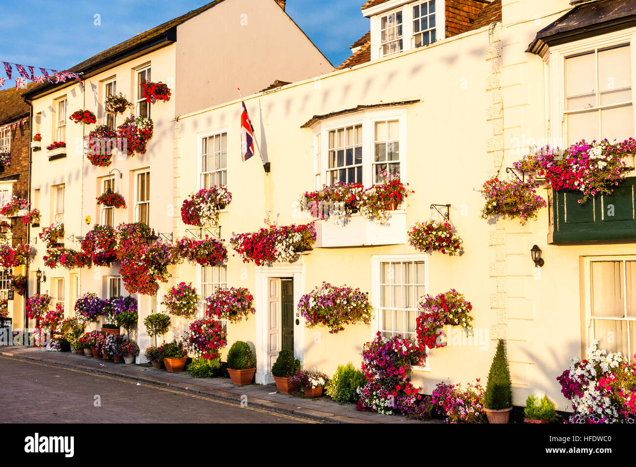 England, Deal. View along row of 17th and 18th century buildings along seafront, all decked with red flowers in boxes. Picturesque. Sunlit. Union Jack. Stock Photo