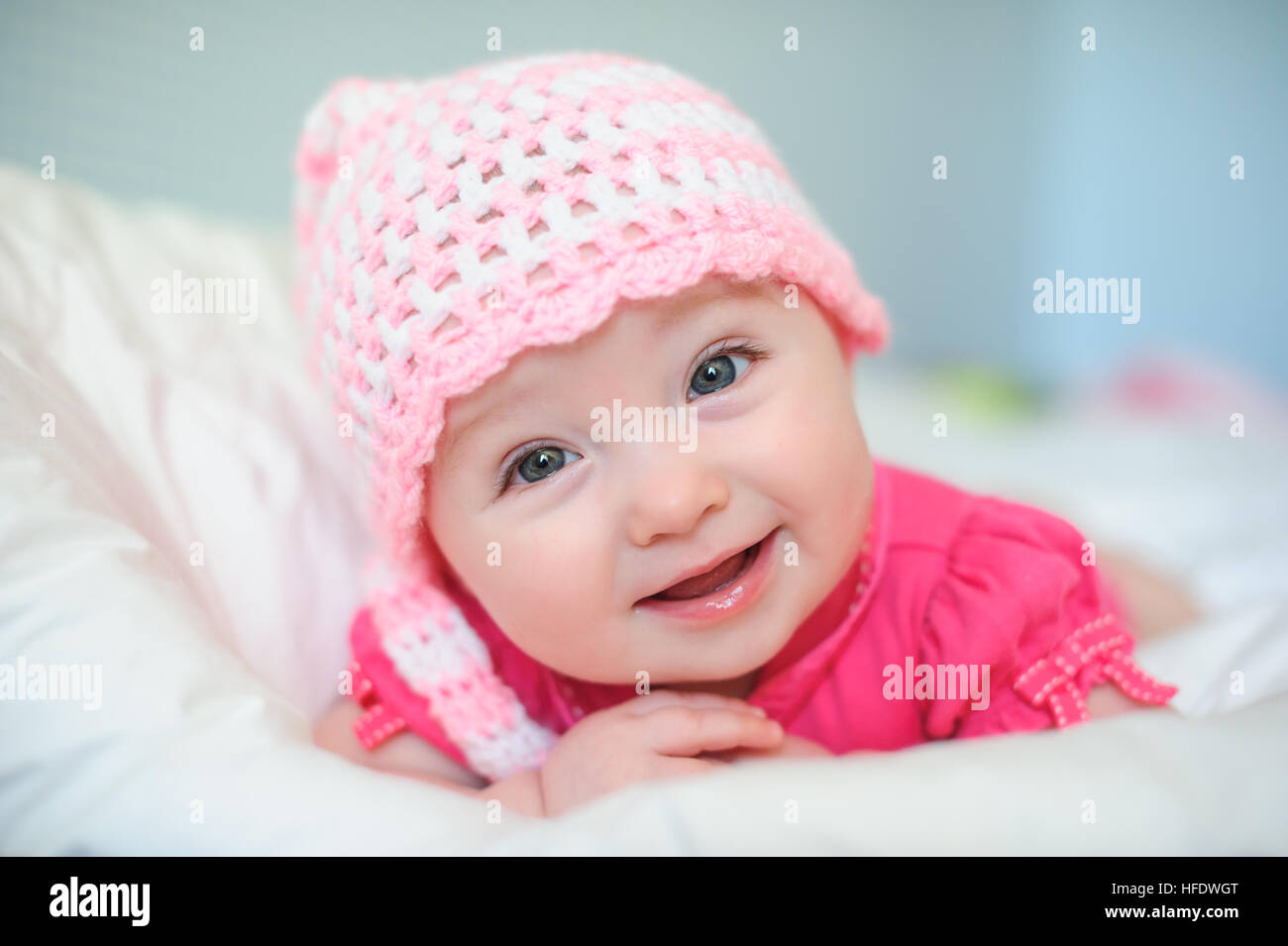 little girl in a knitted hat lying on the bed Stock Photo