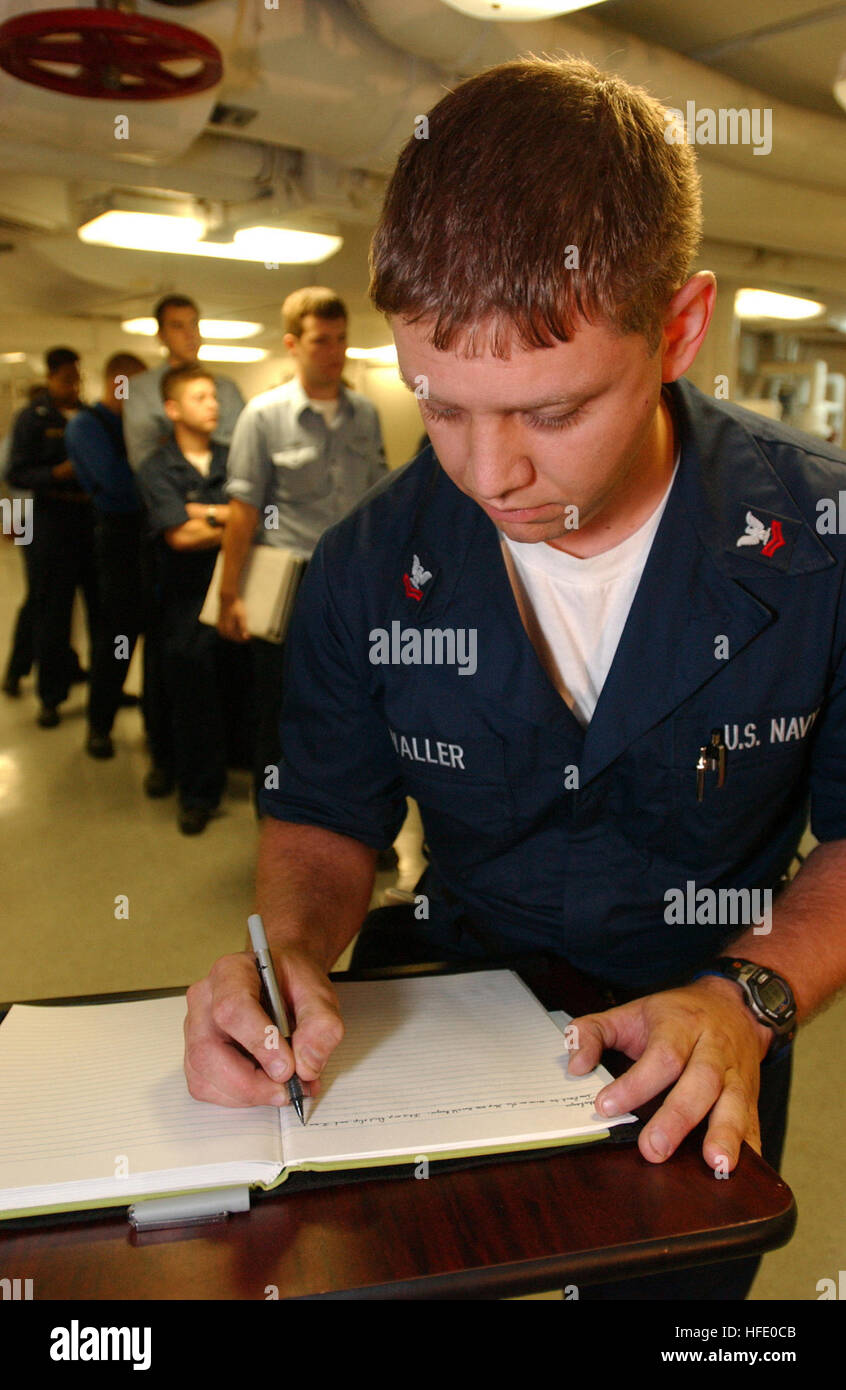 040607-N-2788L-191 Aboard USS Ronald Reagan (CVN 76), June 7, 2004 - Machinist Mate 2nd Class Thomas Waller, from Lexington, Neb., writes a personal message in a book, which is going to be presented by USS Ronald Reagan's (CVN 76) Commanding Officer, Capt. James A. Symonds to Nancy Reagan during President Ronald Regan's internment ceremony, while others wait in line to write their own personal message. The aircraft carrier Ronald Reagan is in the South Atlantic Ocean circumnavigating South America during its transit to  its new homeport of San Diego. U.S. Navy photo by Photographer's Mate Airm Stock Photo