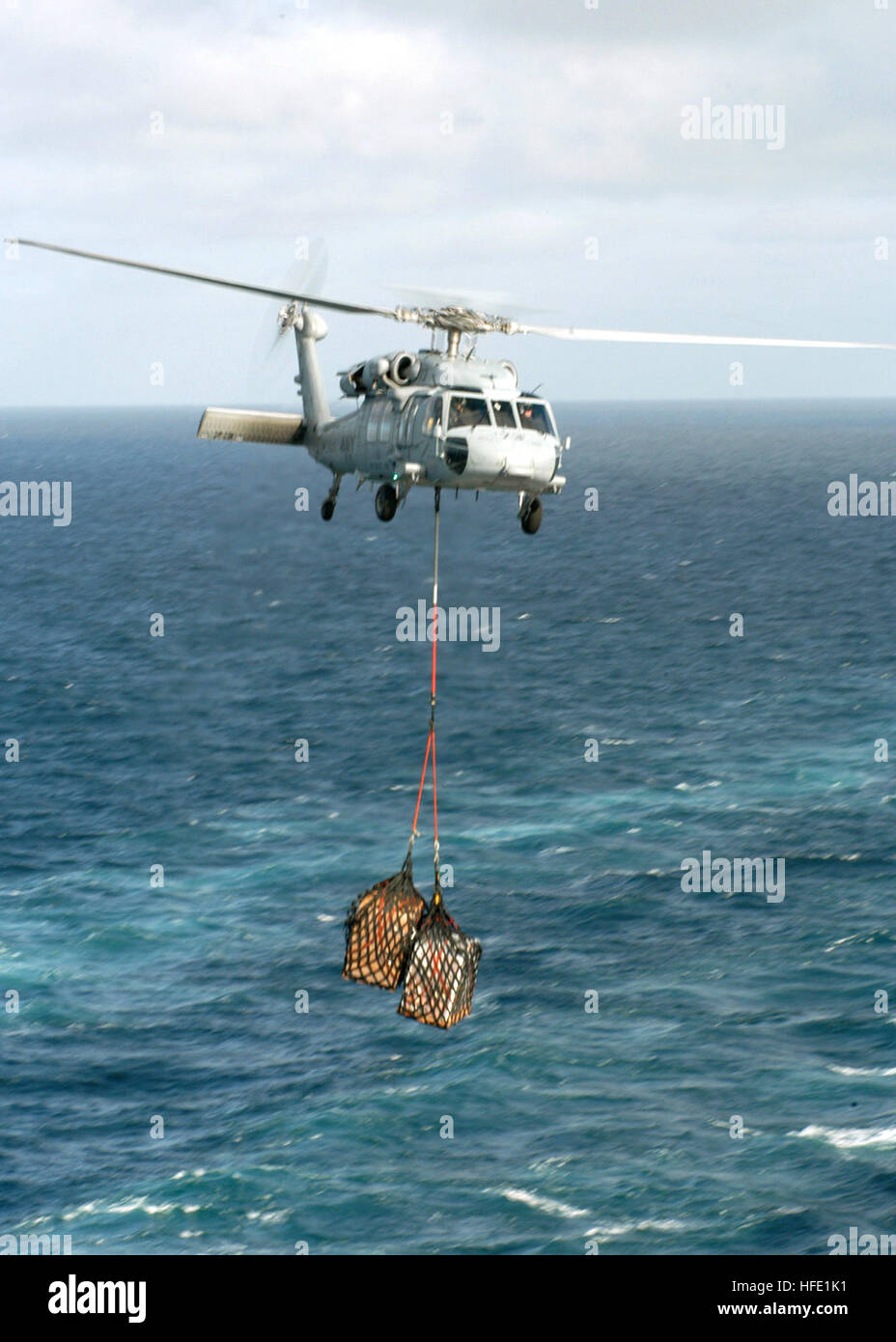 040701-N-7408M-012 Atlantic Ocean (July 1, 2004) - An MH-60S Knighthawk assigned to the 'Chargers' of Helicopter Combat Support Squadron Six (HC-6) carries cargo between the fast combat support ship USS Detroit (AOE 4) and the nuclear-powered aircraft carrier USS Enterprise (CVN 65), during a vertical replenishment at sea. Enterprise is one of seven aircraft carriers involved in Summer Pulse 2004. Summer Pulse 2004 is the simultaneous deployment of seven aircraft strike groups (CSGs), demonstrating the ability of the Navy to provide credible combat across the globe, in five theaters with other Stock Photo