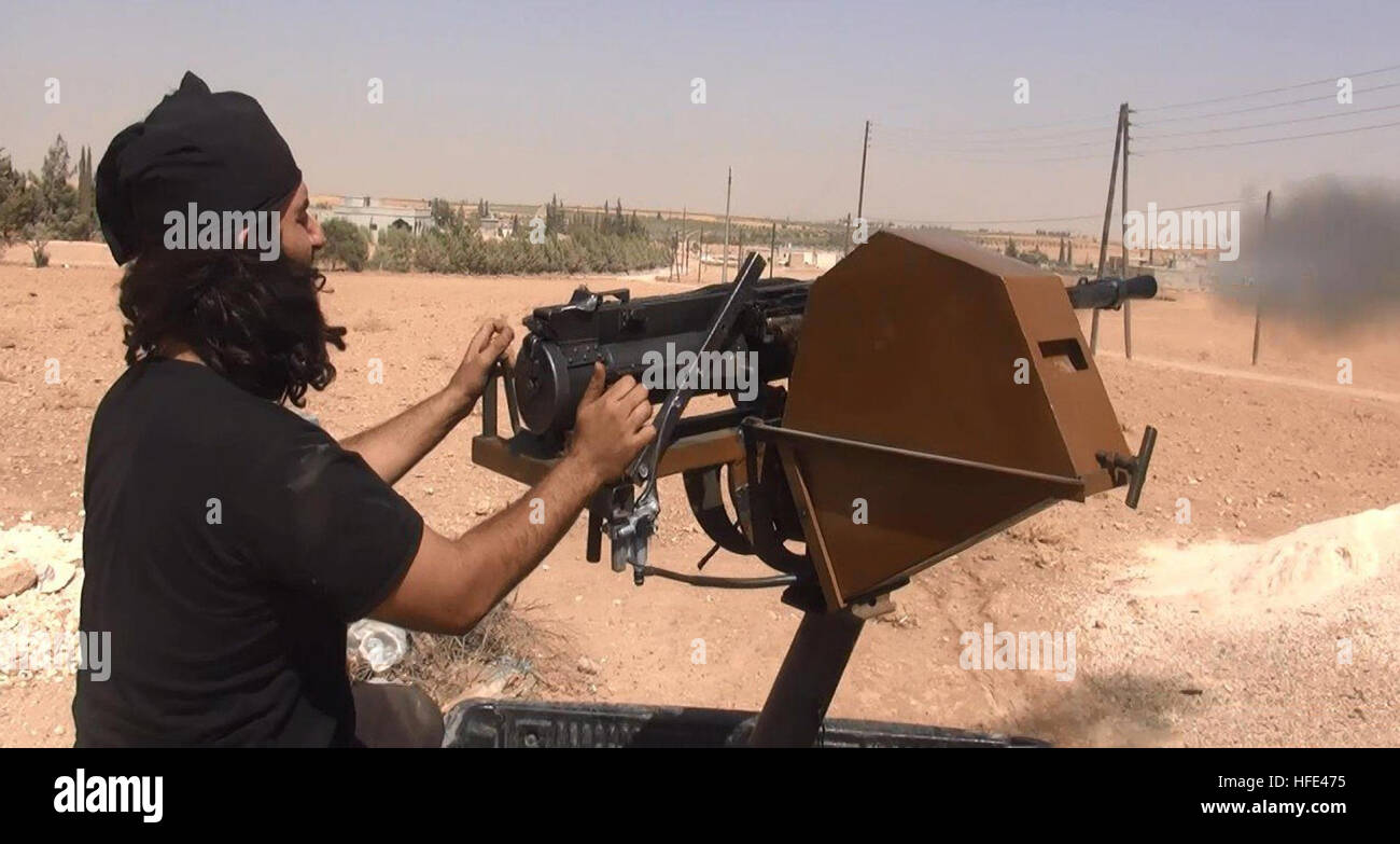Still image taken from an ISIS propaganda video showing an Islamic State fighters firing a heavy machine gun from the back of a pickup truck in a battle against Kurdish forces July 18, 2016 near Manbij, Aleppo province, Syria. Stock Photo
