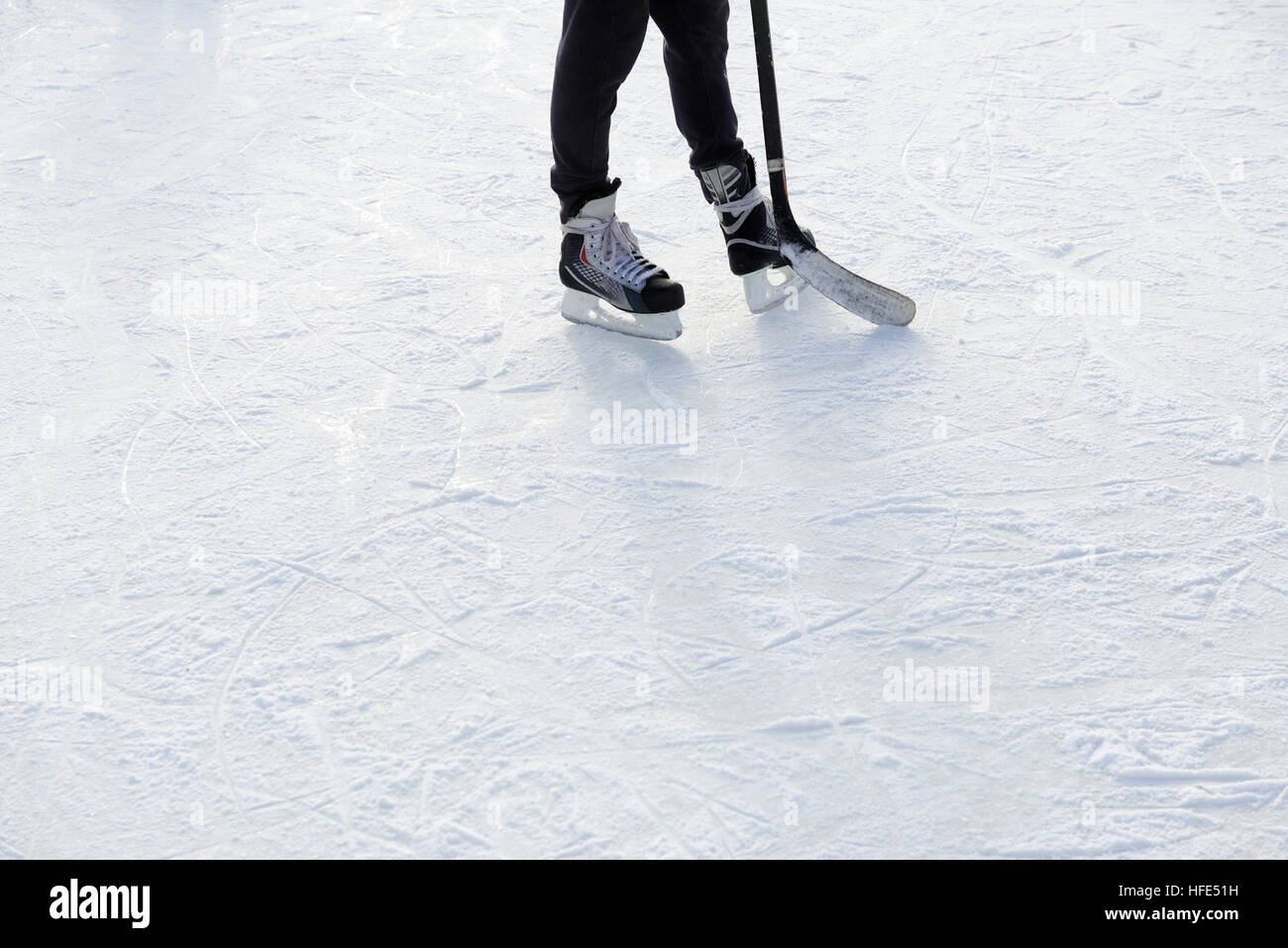 Outdoor Ice skating. Hockey player's legs and skates on ice rink. Stock Photo