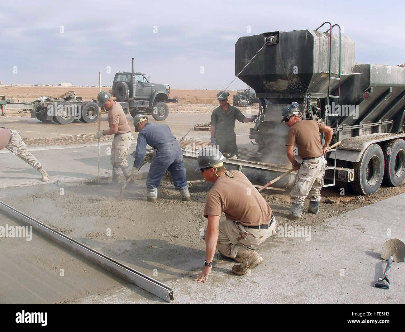 041119-N-5386H-027 Al Asad, Iraq (Nov. 19, 2004) - Reserve Seabees assigned to Naval Mobile Construction Battalion Two Three (NMCB-23), pour concrete as they work to complete an extensive repair job which includes making permanent repairs to 39 swimming pool-size impact craters on different sections of the Al Asad airfield runways. The craters, a result of bombing during the 2003 invasion of Iraq, have left the airfield inoperable for more than a year. U.S. Navy photo by PhotographerÕs Mate 2nd Class Michael D. Heckman (RELEASED) US Navy 041119-N-5386H-027 Reserve Seabees assigned to Naval Mob Stock Photo