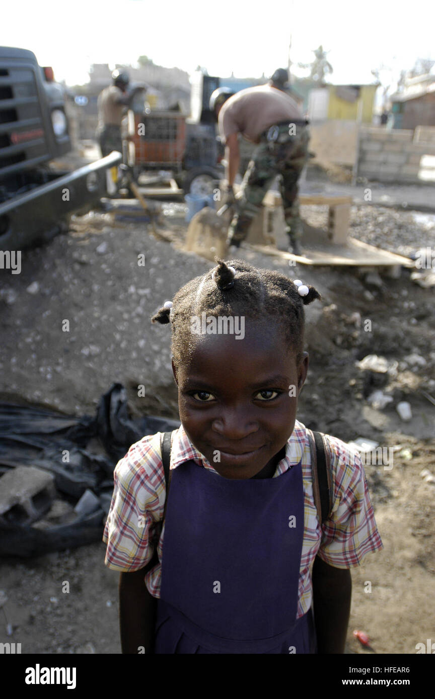 050310-N-0411D-008 Gonaives, Haiti (Mar. 10, 2005) Ð A young child smiles as U.S. Navy Seabees assigned to Naval Mobile Construction Battalion One (NMCB-1), construct a new school building for her and her classmates in Gonaives, Haiti.  After the hurricanes of 2004, floodwaters were more than 12 feet deep at this location.  When asked what she thought of the work being done, she said, 'Tres bien,' which translates to 'very good.' NMCB-1 is part of the New Horizon Task Force, which is deployed to Haiti for three months to conduct humanitarian construction and medical assistance. The constructio Stock Photo