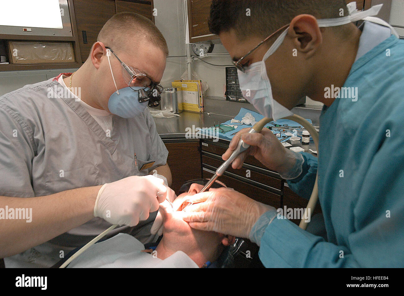 040126-N-3986D-001  Atlantic Ocean (Jan. 26, 2004) - Lt. Joe Wigfield, from Magnolia, Ohio, and Dental Technician Miguel Hernandez from Puerto Rico, apply a tooth filling to a crew member aboard USS George Washington (CVN 73).  The Norfolk, Va.-based nuclear powered aircraft carrier is on a routine scheduled deployment.  U.S. Navy photo by PhotographerÕs Mate Airman Jessica Davis.  (RELEASED) US Navy 040126-N-3986D-001 Lt. Joe Wigfield, from Magnolia, Ohio, and Dental Technician Miguel Hernandez from Puerto Rico, apply a tooth filling to a crew member aboard USS George Washington (CVN 73) Stock Photo