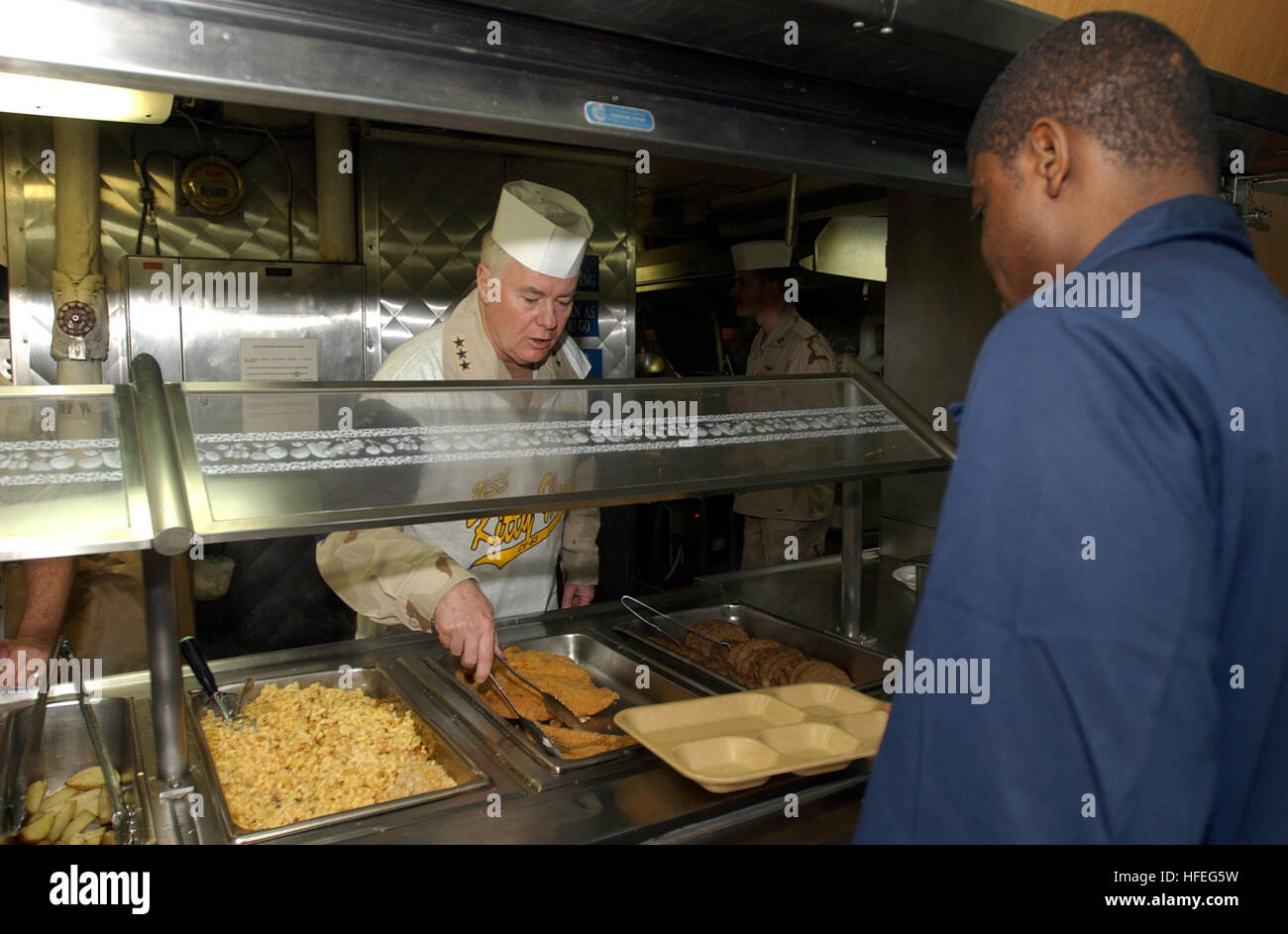 030301-N-0120R-009  Arabian Gulf (Mar. 1, 2003) -- Vice Adm. Timothy Keating, Commander, U.S. Naval Forces Central Command, pitches in and helps serve a meal to the crew during his resent tour of the aircraft carrier USS Kitty Hawk (CV 63). Kitty Hawk and its embarked Carrier Air Wing Five (CVW-5) is operating with coalition forces in the Arabian Gulf and is the worldÕs only permanently forward-deployed aircraft carrier and operates out of Yokosuka, Japan.  U.S. Navy photo by PhotographerÕs Mate 3rd Class William H. Ramsey.  (RELEASED) US Navy 030301-N-0120R-009 Vadm. Keating visits USS Kitty  Stock Photo