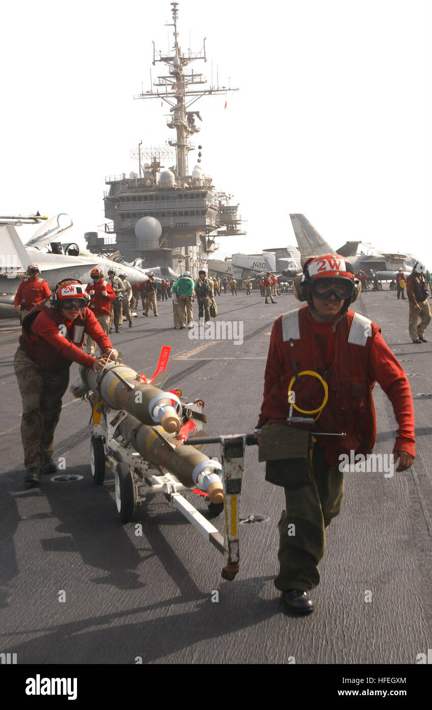 030320-N-1810F-007 The Arabian Gulf (Mar. 20, 2003) -- Aviation ordnancemen relocate 2,000-lb. GBU-31 Joint Defense Attack Munitions (JDAMs), for uploading to aircraft aboard USS Kitty Hawk (CV 63). JDAMs are guidance kits that convert existing unguided bombs into precision-guided 'smart' munitions. The tail section contains an inertial navigational system (INS) and a global positioning system (GPS). A JDAM improves the accuracy of unguided bombs in any weather condition.  Kitty Hawk is operating with coalition forces in support of Operation Iraqi Freedom, the multi-national coalition effort t Stock Photo