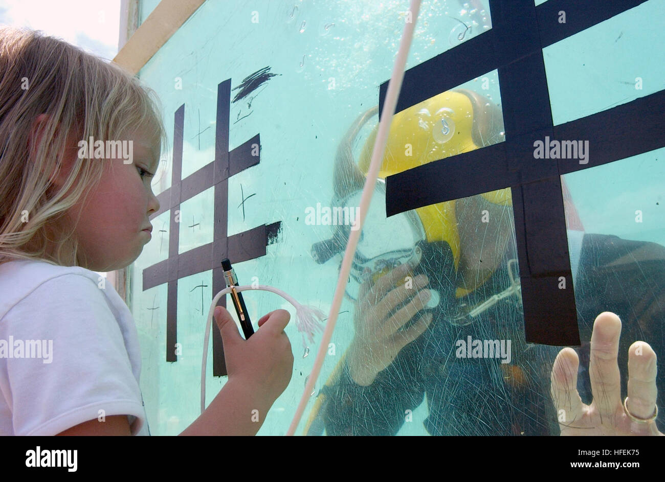 030504-N-3994W-001  Honolulu, Hawaii (May 4, 2003) -- A girl ponders her next move while playing a game of tic-tac-toe with submerged Sonar Technician 1st Class Geoff Smitman assigned to Mobile Diving and Salvage Unit One (MDSU-1) at the Bishop Museum during a Family Sunday-Military Appreciation Day. AIG Hawaii, an insurance company, sponsored free admission for military members and their families to the museum while the general public had discounted admission, as well.  In addition to the regular museum exhibits, several military commands hosted booths including displays from SEAL Delivery Ve Stock Photo