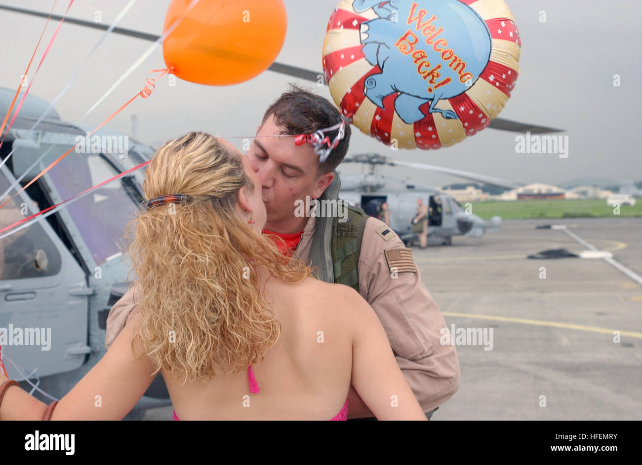 030725-N-7805K-002  Atsugi, Japan (July 25, 2003) -- Lt. j.g. Aaron Kemp is met on the flight line by his wife carrying 'Welcome Back' balloons during the homecoming celebration for the ÒWar LordsÓ of Helicopter Anti-Submarine Squadron Light Five One (HSL-51).  The ÒWar LordsÓ are returning from a six-month deployment in support of Operation Iraqi Freedom.  U.S. Navy photo by PhotographerÕs Mate 3rd Class Shaun Knittel.  (RELEASED) US Navy 030725-N-7805K-002 Lt. j.g. Aaron Kemp is met on the flight line by his wife carrying Welcome Back balloons during the homecoming celebration for the War Lo Stock Photo