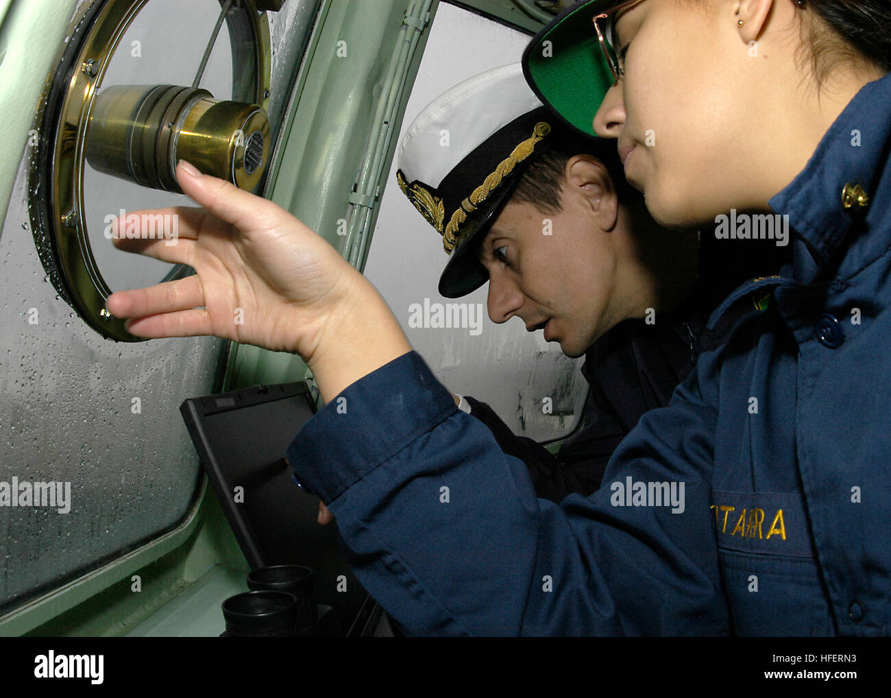 031205-N-0399H-033 Aboard Yard Patrol Craft 698 (YP 698) Dec. 5, 2003 -- Midshipman 2nd Class Mirel Gutarra, from Lima, Peru, makes visual contact with aids of navigation and reports her findings to Lt. Cmdr. Paolo Lombardi, an exchange instructor at the U.S. Naval Academy from Laspezia, Italy, from the bridge of Yard Patrol Craft 698 (YP 698) as it makes its way to Coast Guard Station Philadelphia. The boat and crew are part of a formation of three Yard Patrol Crafts, which made the transit the 104th playing of the Army Navy game. The Navy went on to defeat the Black Knights of Army by a scor Stock Photo